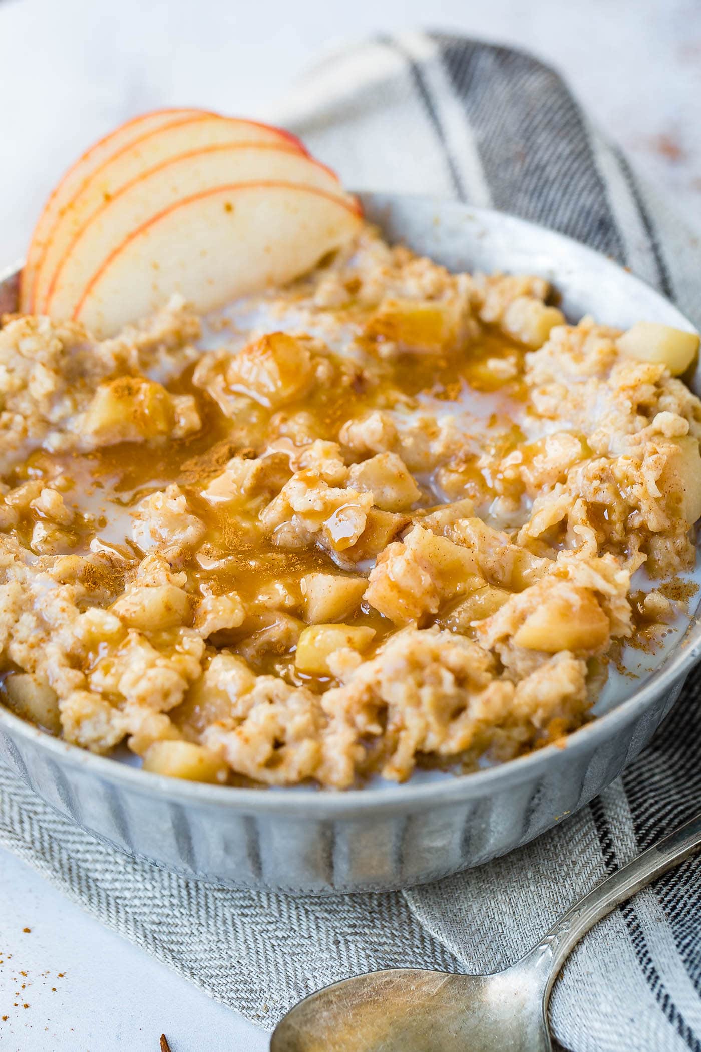 A photo of apple pie slow cooker oatmeal topped with caramel and thinly sliced apples.
