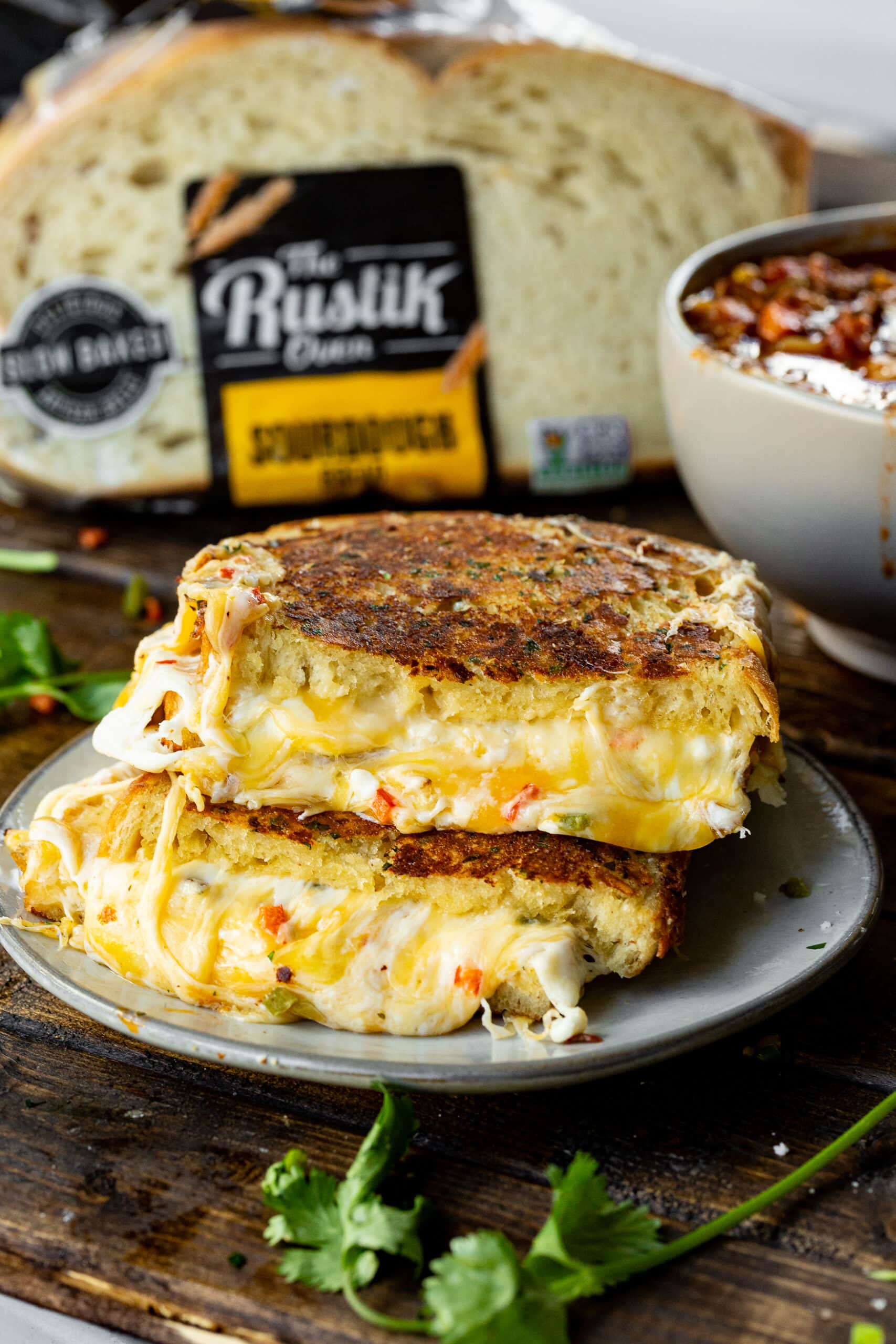 a photo of a golden grilled cheese sandwich that has been cut in half and stacked on top of each other with the facing the camera and gooey cheese melting out all the sides.
