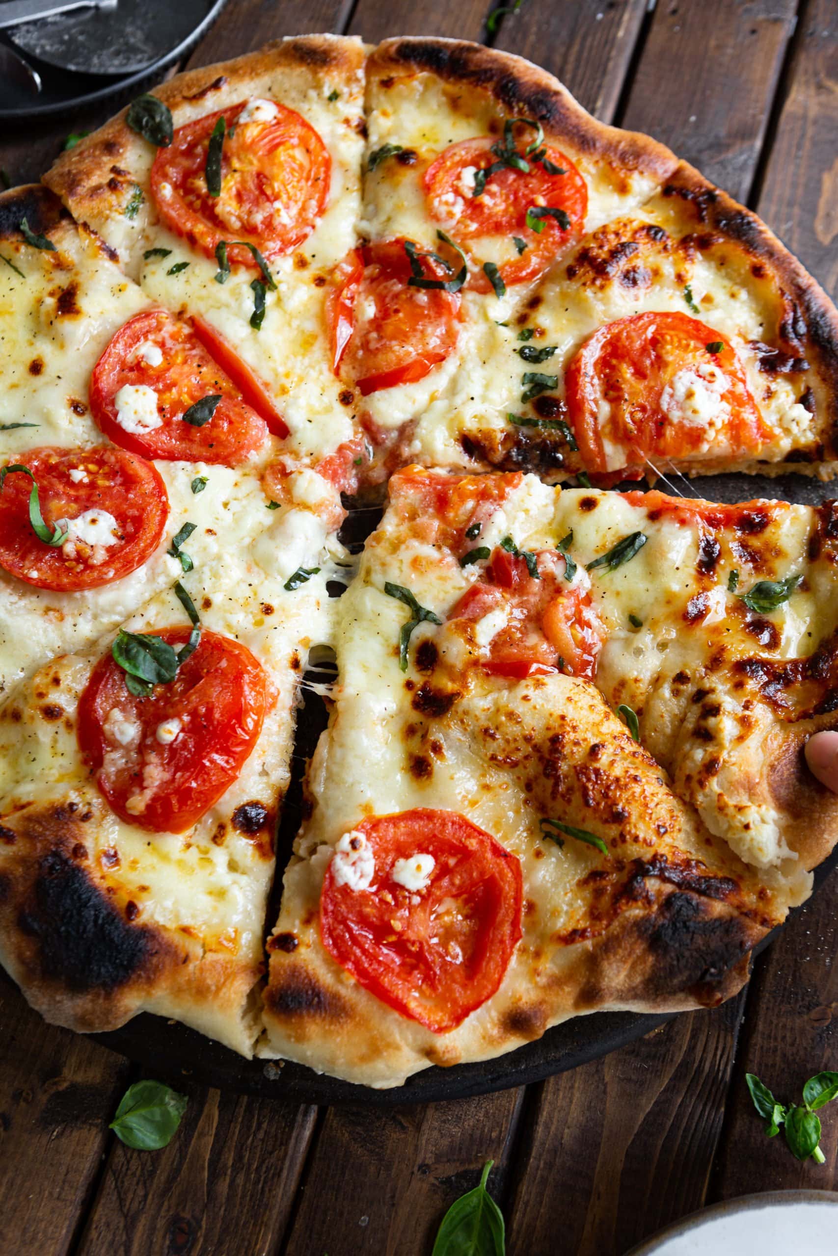 a photo of a four cheese margherita pizza that has been sliced with two of slices pulled out from the rest of the pizza a little bit.