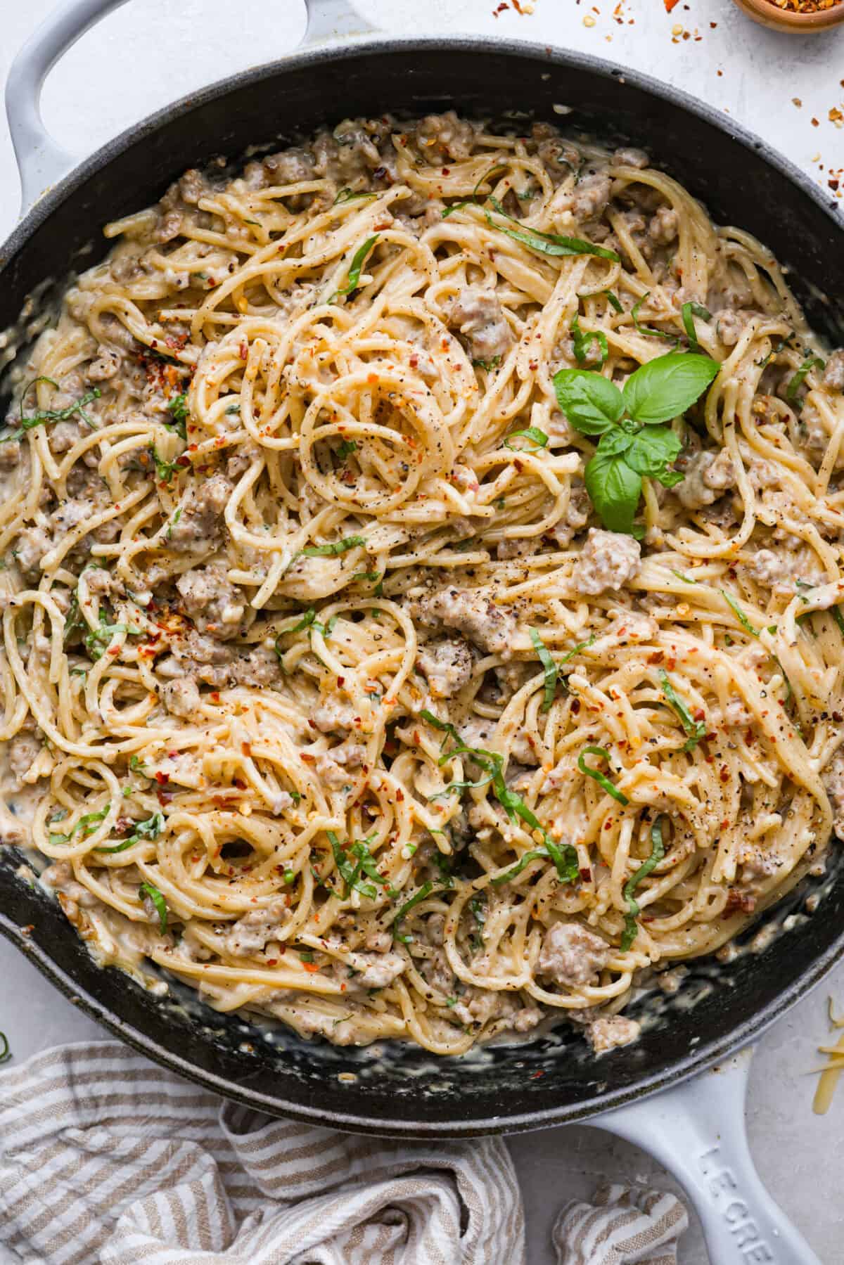 Overhead shot of the skillet full of cooked creamy sausage spaghetti ready to serve. 