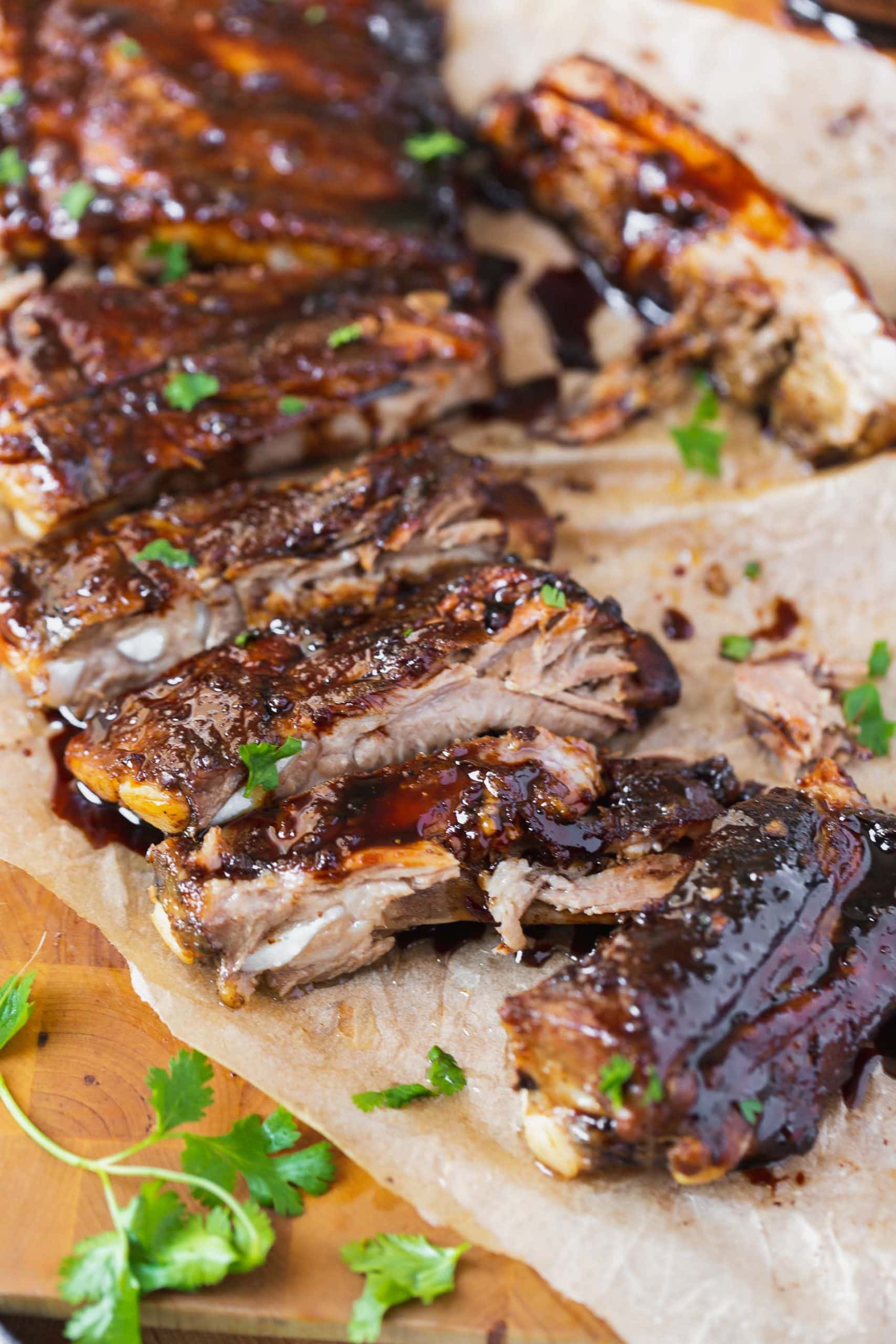 a photo of a rack of asian sticky ribs that have been all cut apart topped with sesame seeds and chopped cilantro.