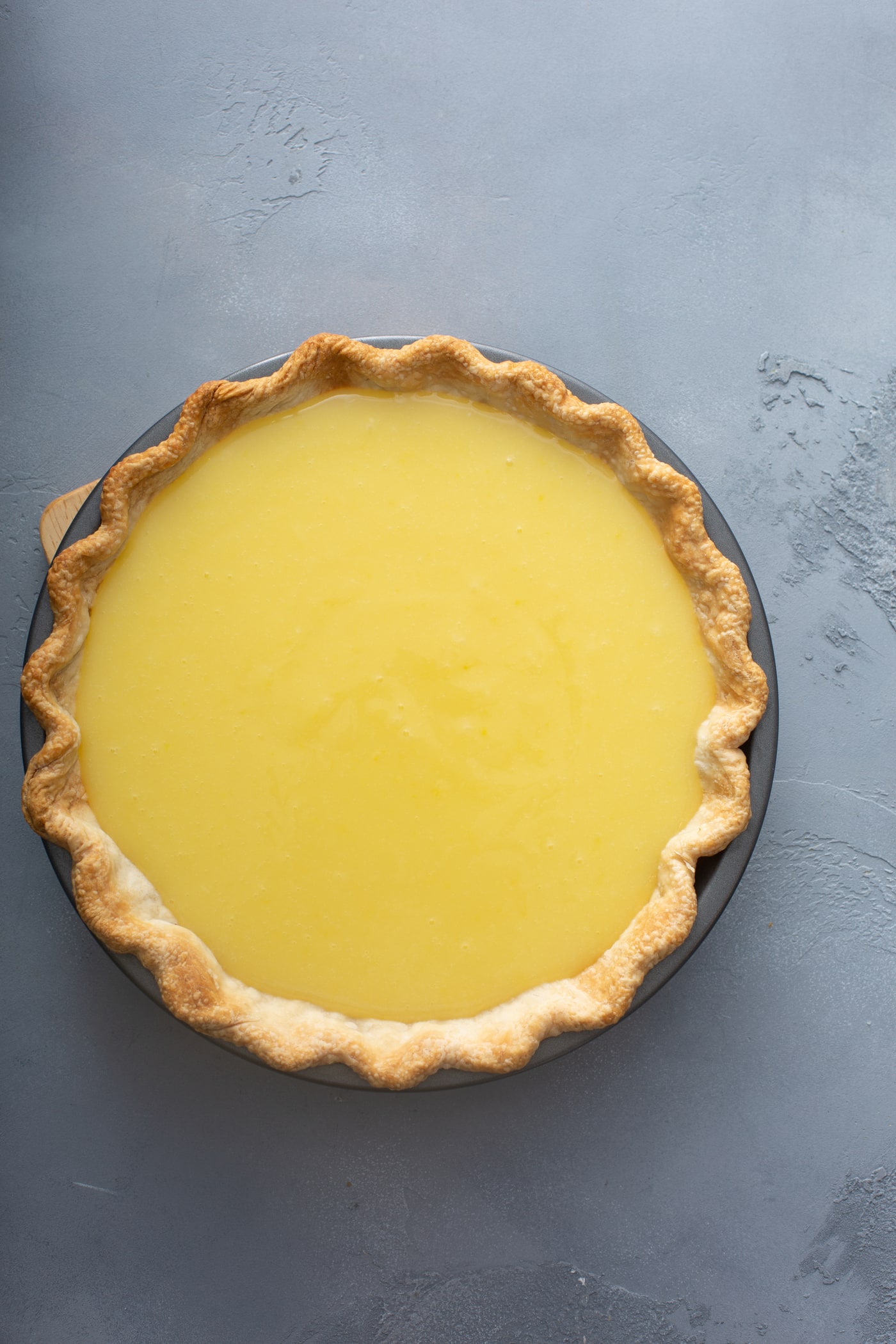 A picture or a lemon pie. The filling is bright yellow and the crust is light golden brown.