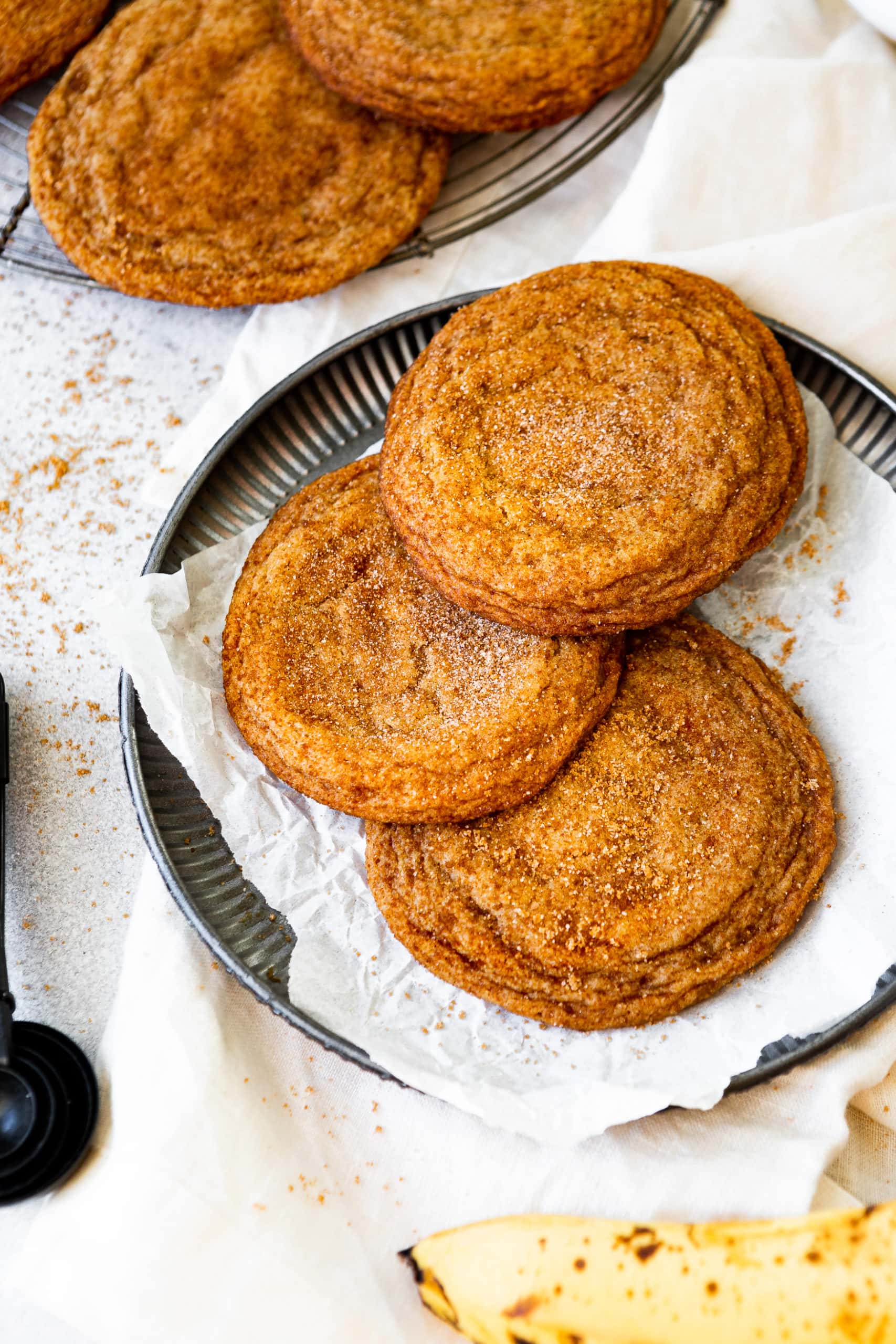 a photo of a three golden baked banana cookies sitting on a white napkin on top of a small saucer.