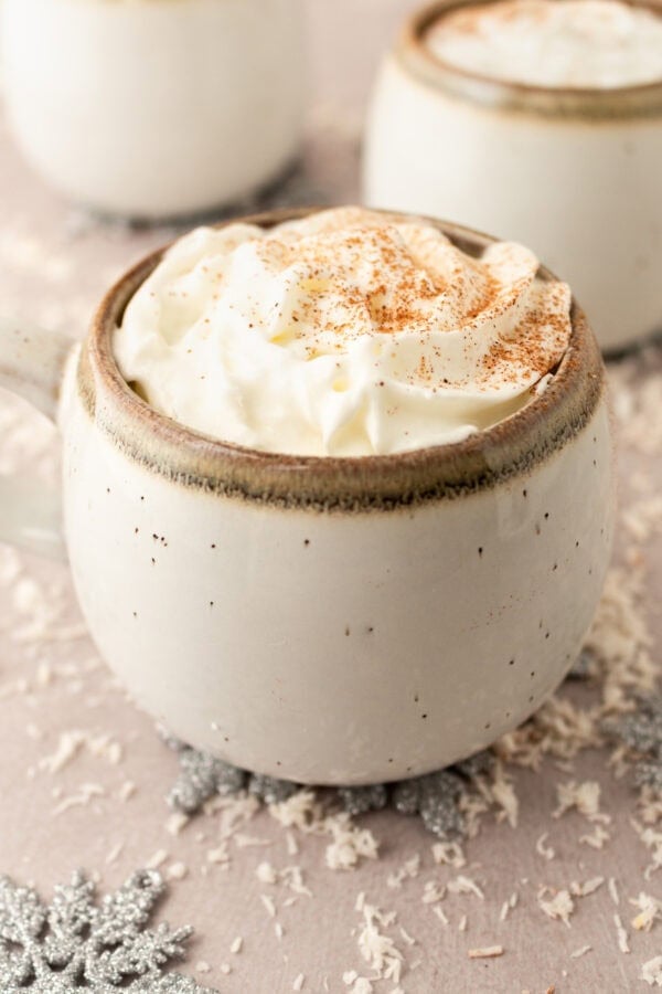 a photo of a mug of warm vanilla milk topped with whipped cream at sprinkled with cinnamon