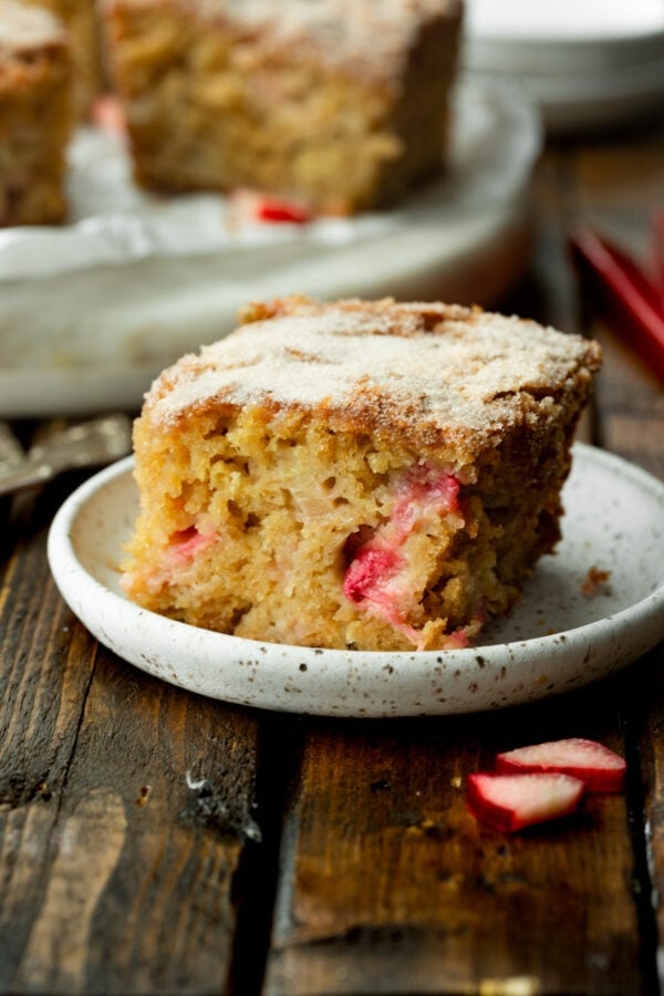 a photo of a piece of rhubarb cake loaded with chunks of tender rhubarb sitting on a small dessert plate.