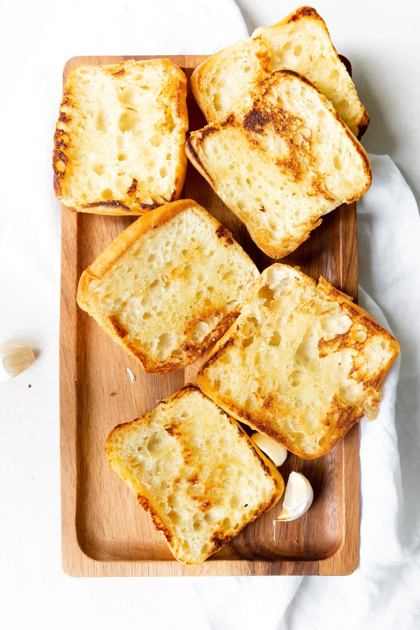 a photo of 5 ciabatta rolls sliced open and face up and golden toasted.