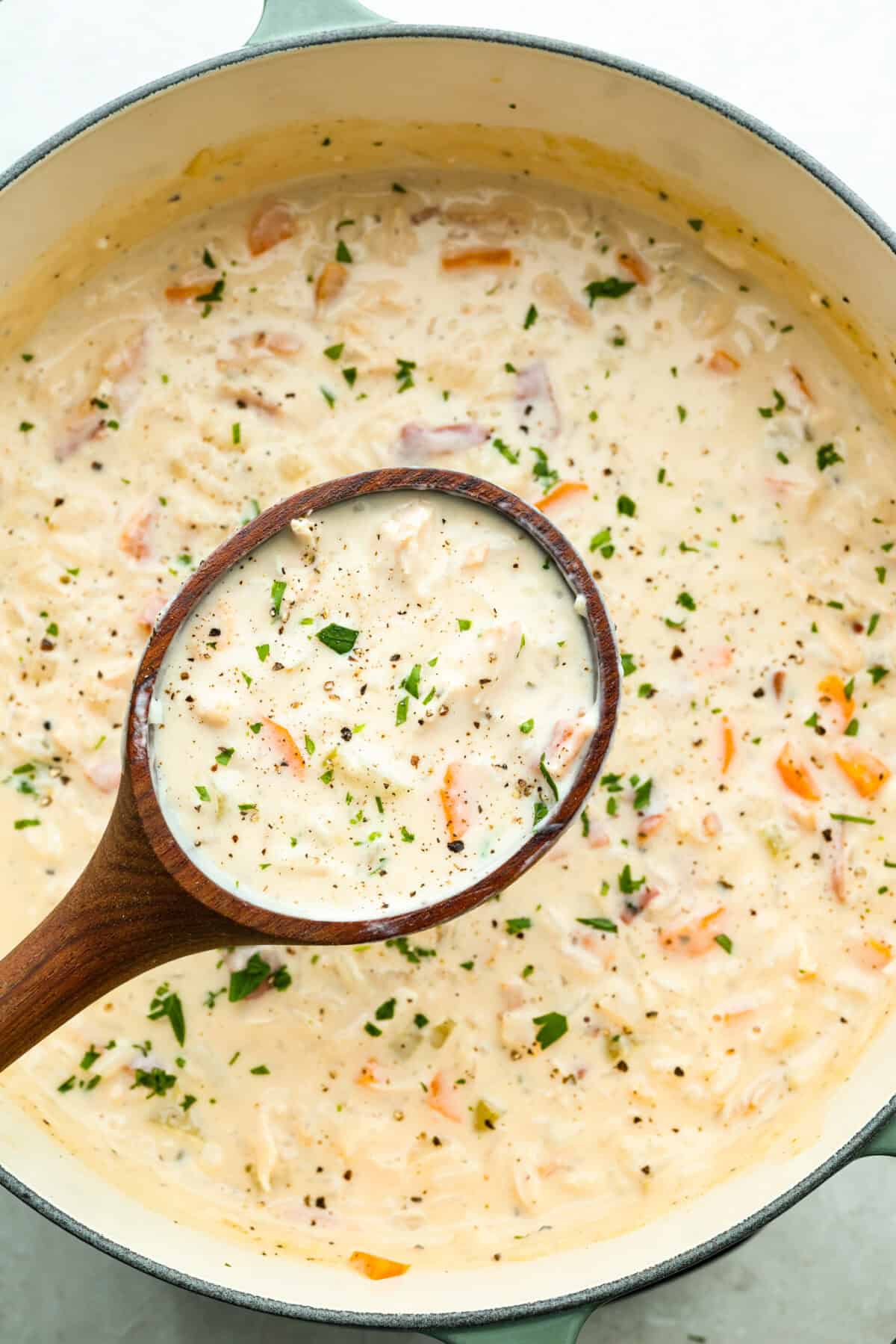 Large pot of soup with a large wooden ladle lifting a scoop of crack chicken and rice soup out of the pot.