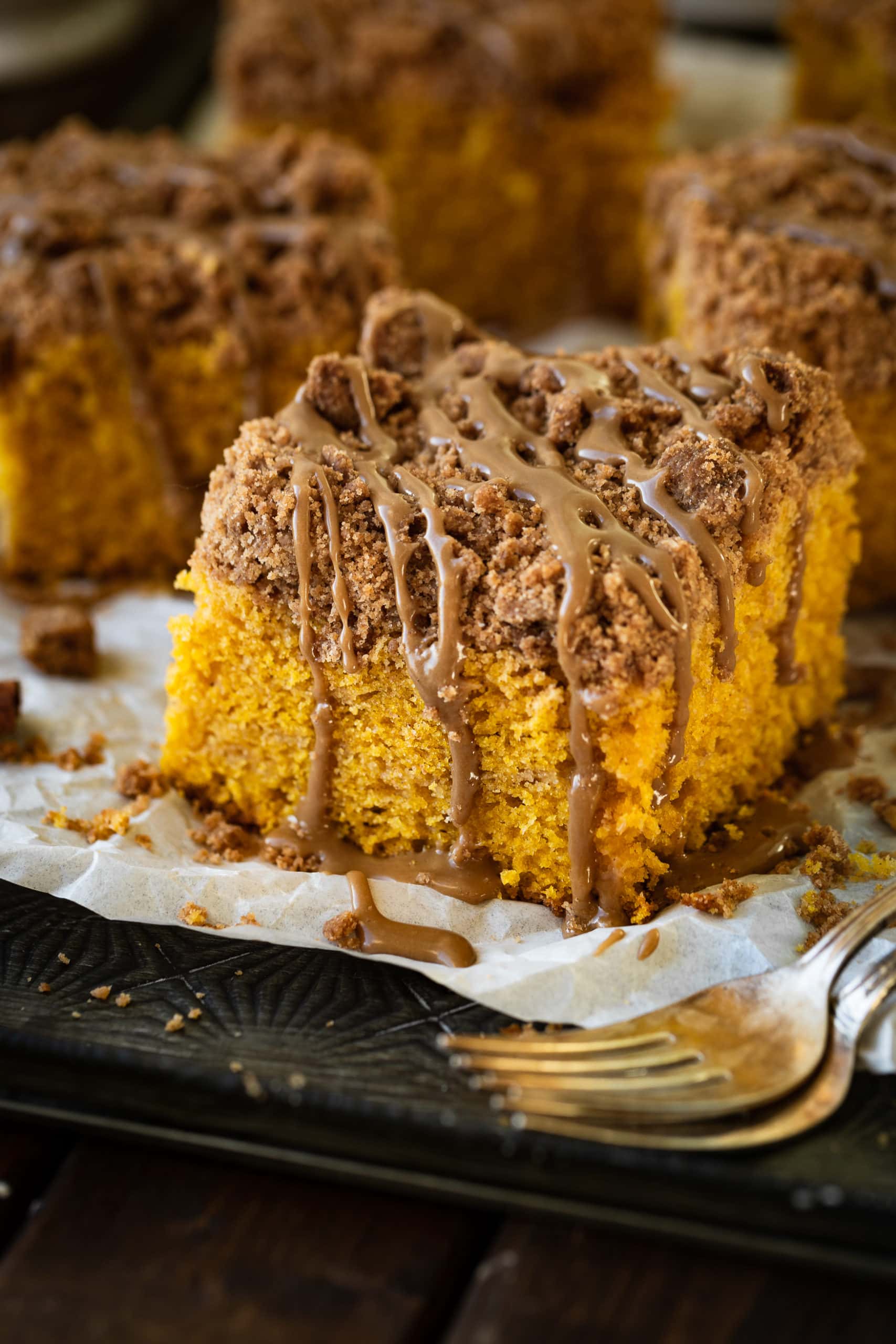 a photo of a single piece of pumpkin coffee cake topped with a cinnamon crumb topping and a maple glaze drizzle.