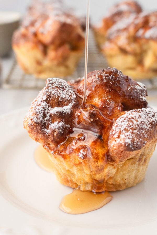 a photo of syrup bring drizzled over a golden french toast muffin dusted with powdered sugar