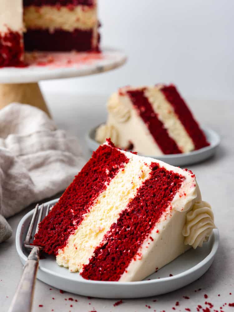 A slice of cake (with another in the background) served on gray plates.