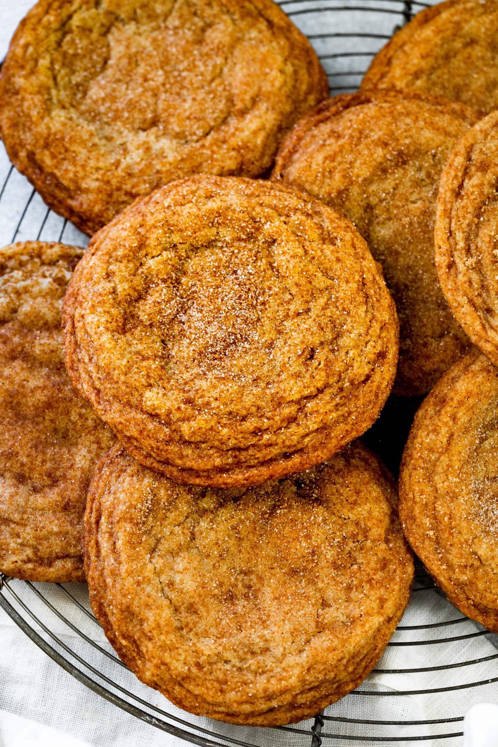 a photo of several baked banan cookies piled on a wire cooling rack.