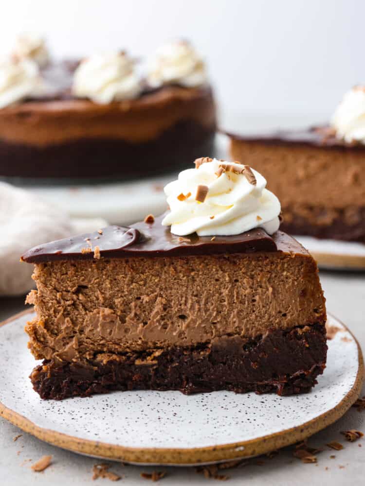 A slice of brownie chocolate cheesecake on a stoneware plate.
