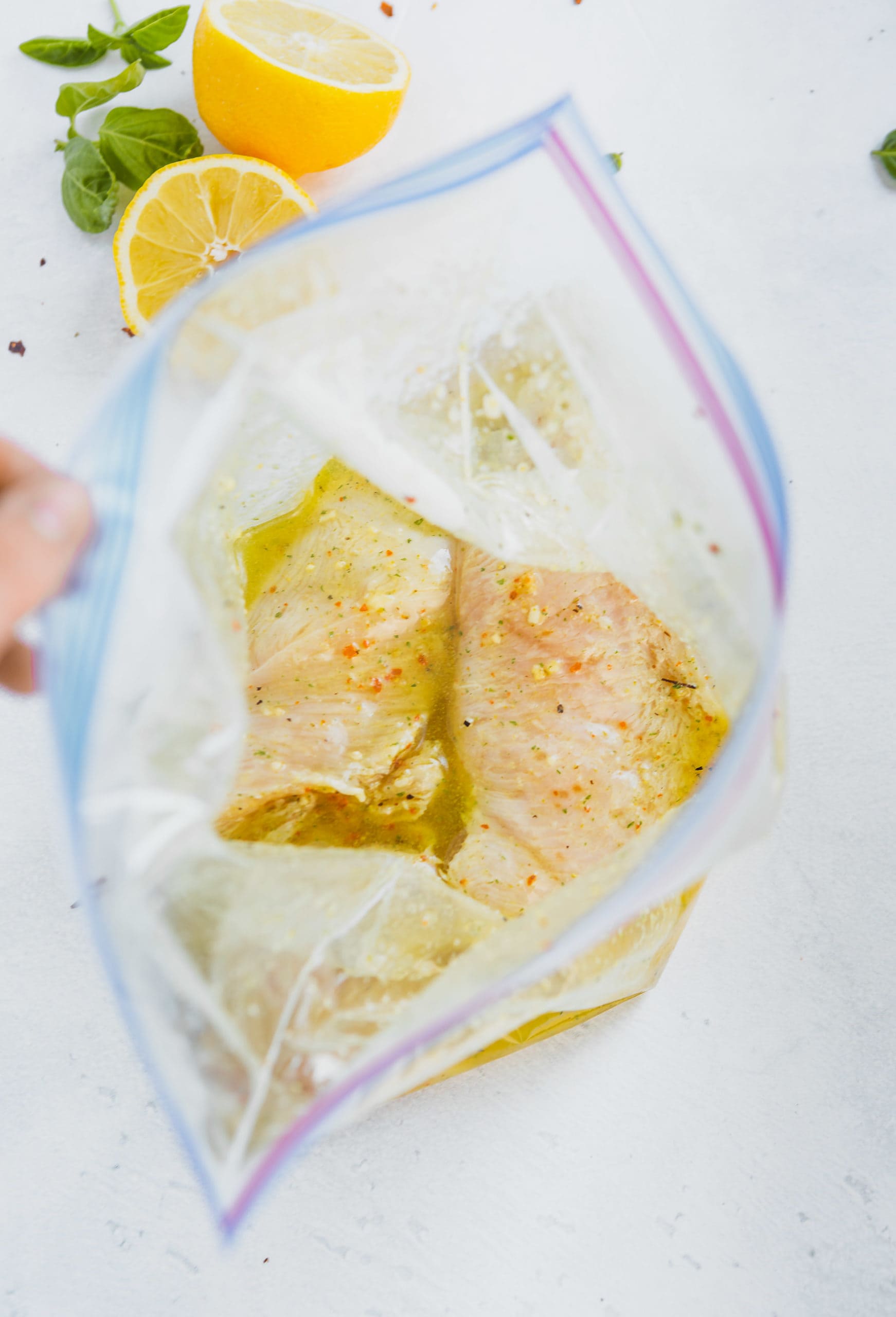 A zip lock bag with chicken breasts in a marinade.