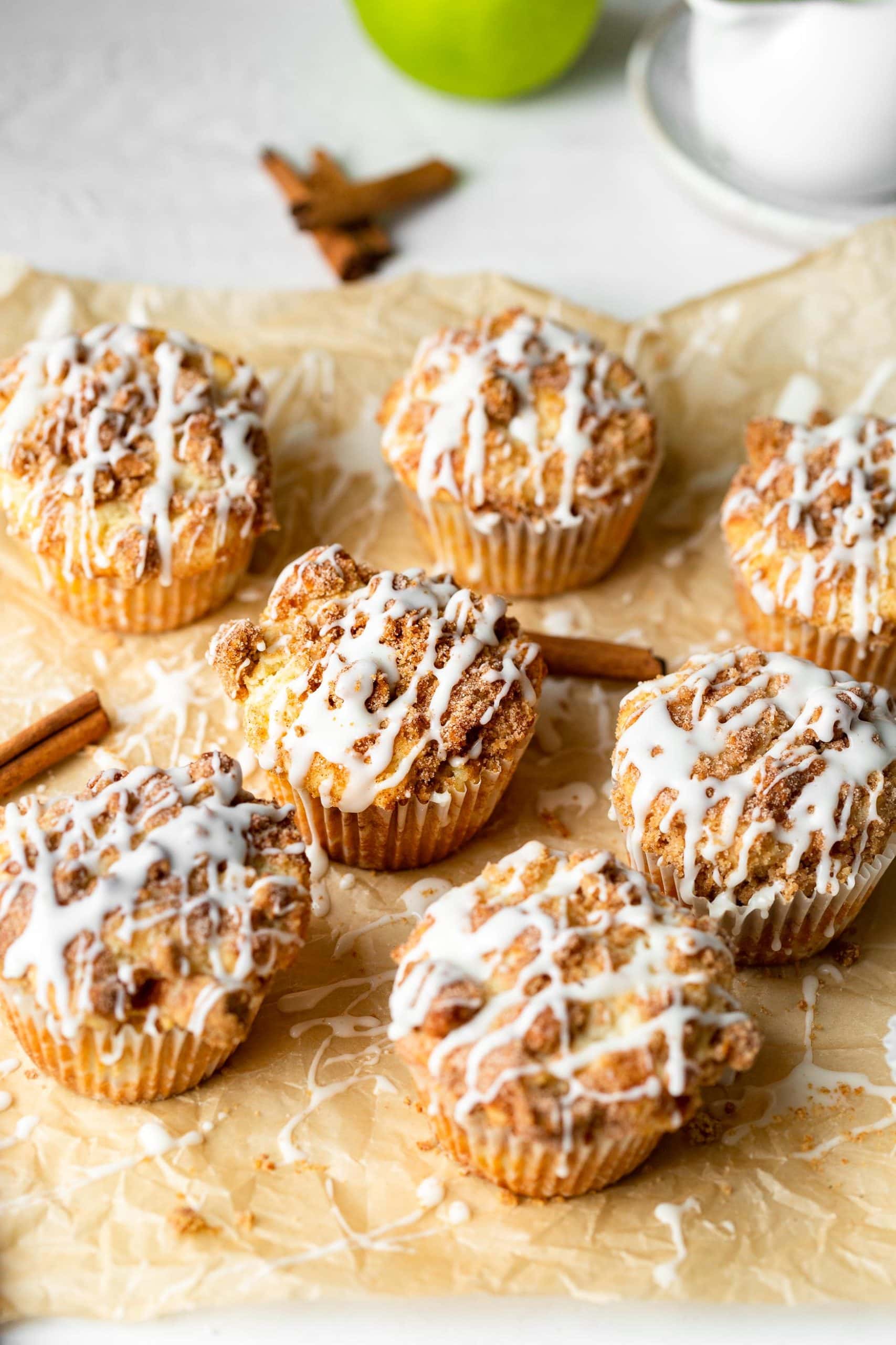 cinnamon sticks laying between apple coffee cake muffins with cinnamon streusel and icing