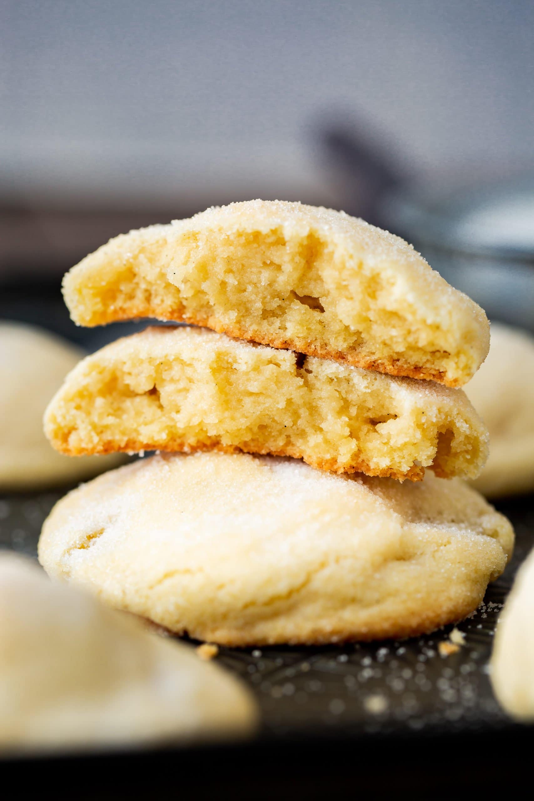 a photo of thick and soft sugar cookies stacked on each other. the top cookie has been broken in half and stacked on each other with the center facing the camera.