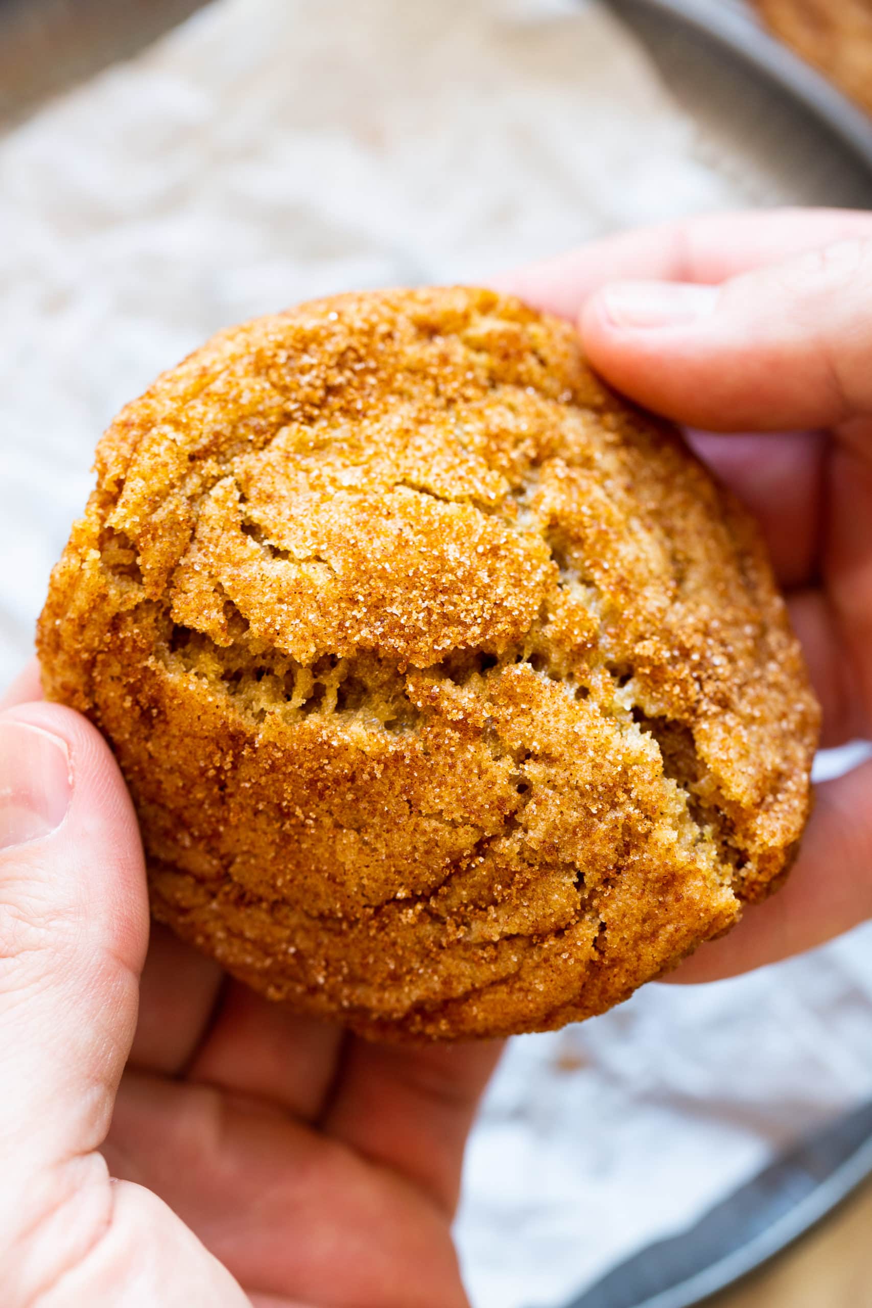 a photo of someone holding a golden banana cookie and breaking it in half.