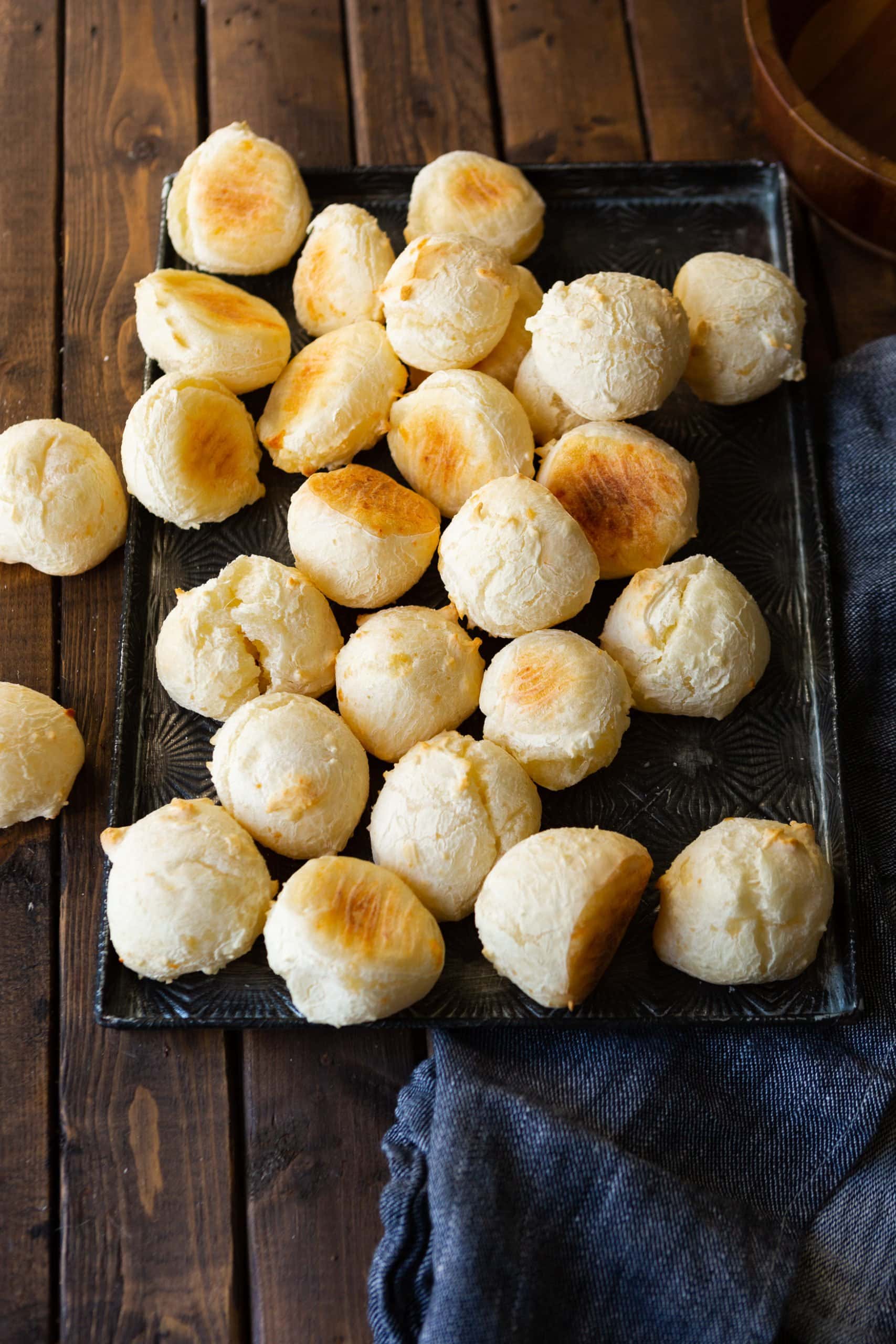 a photo of several golden small cheese bread rolls istting on a wooden table.