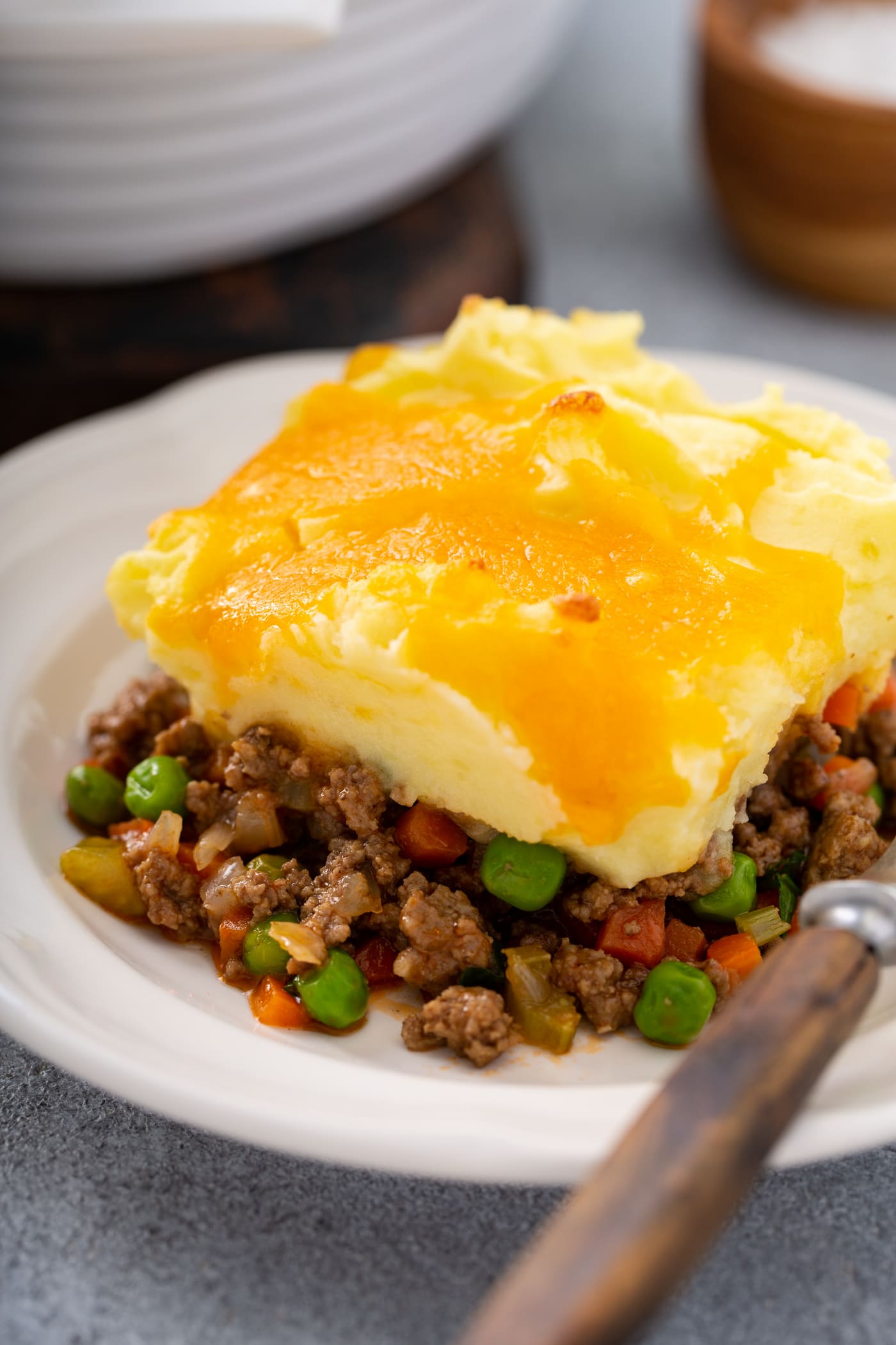 A serving of shepherd's pie on a white plate. there is a fork resting next to it on the plate.