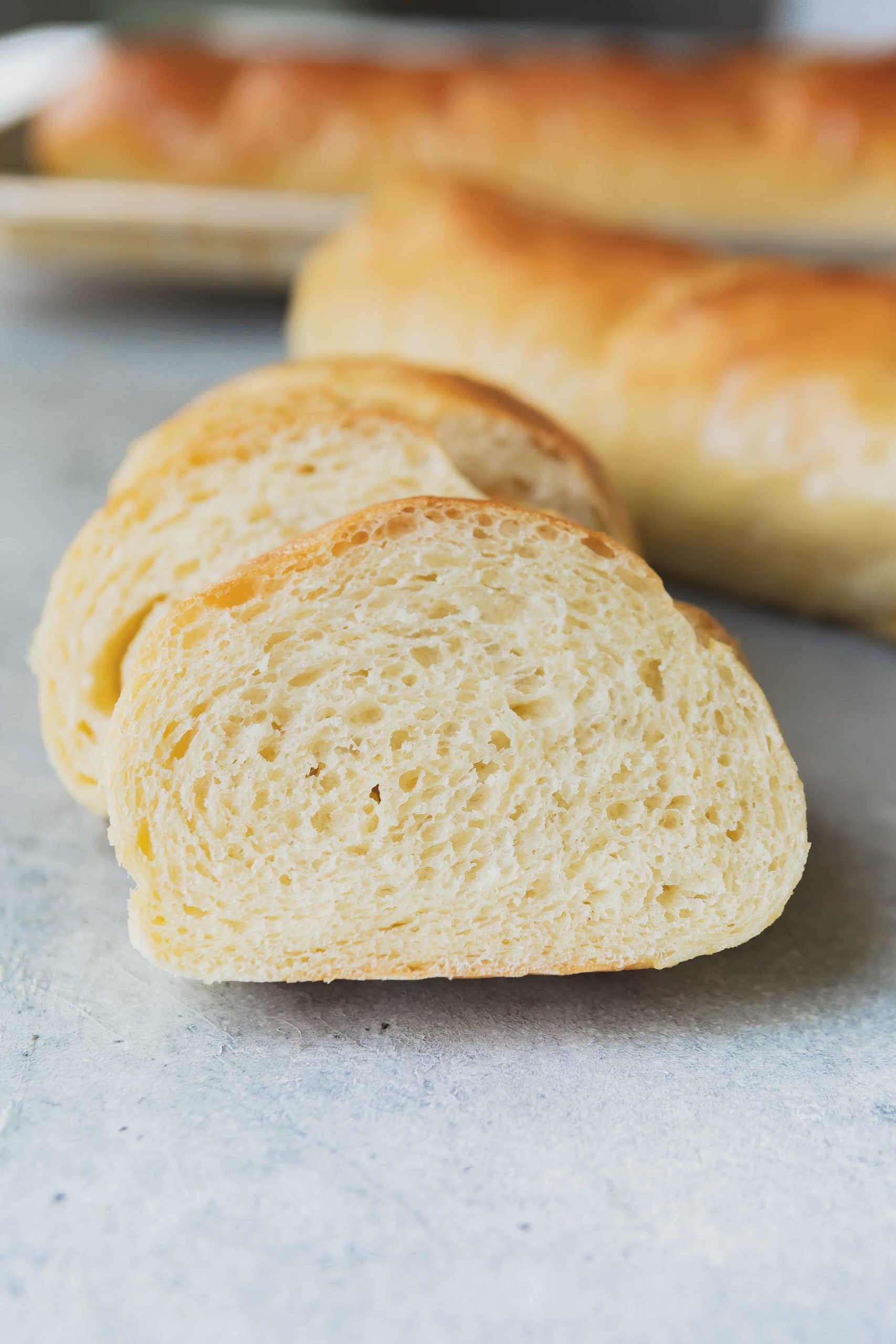 a photo of a slice of french bread leaning up against more slices of french bread with a full loaf in the background a photo of a slice of french bread leaning up against more slices of french bread with a full loaf in the background