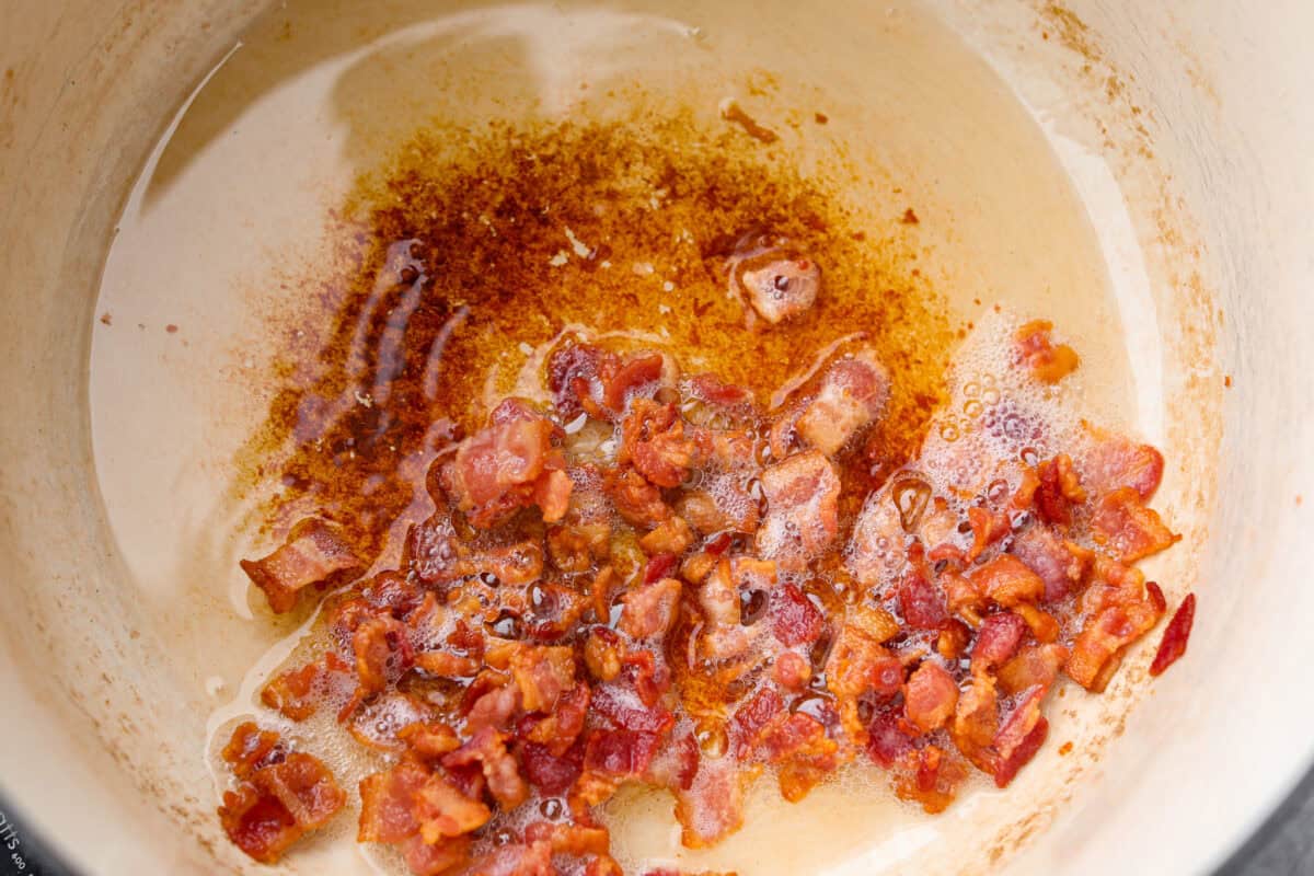 Bacon cooking in the bottom of the dutch oven.