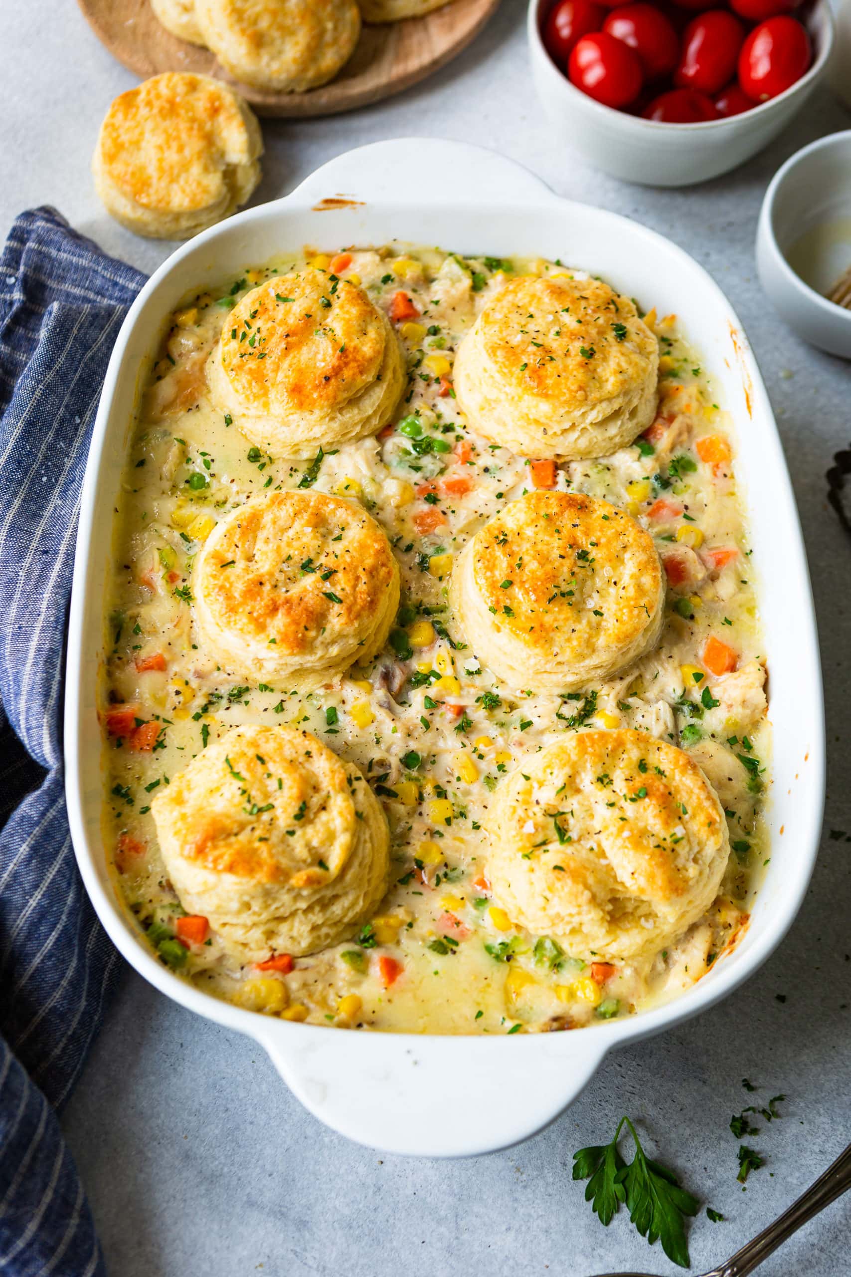 a photo of a large baking dish full of easy biscuit chicken pot pie. the biscuits are golden and perfect and the pot pie filling is creamy and full of veggies and chunks of chicken.