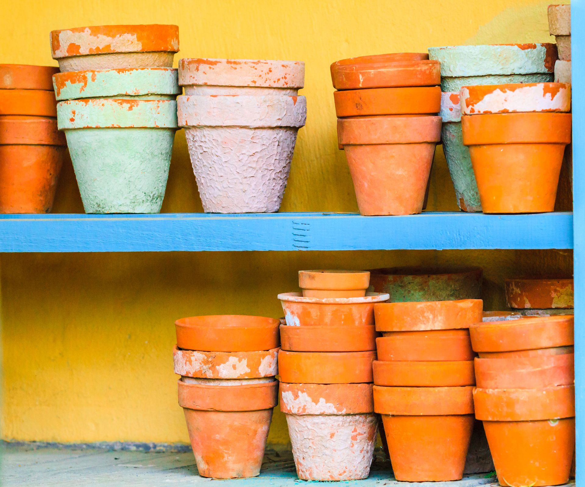small natural and painted terracotta pots stacked on painted shelves