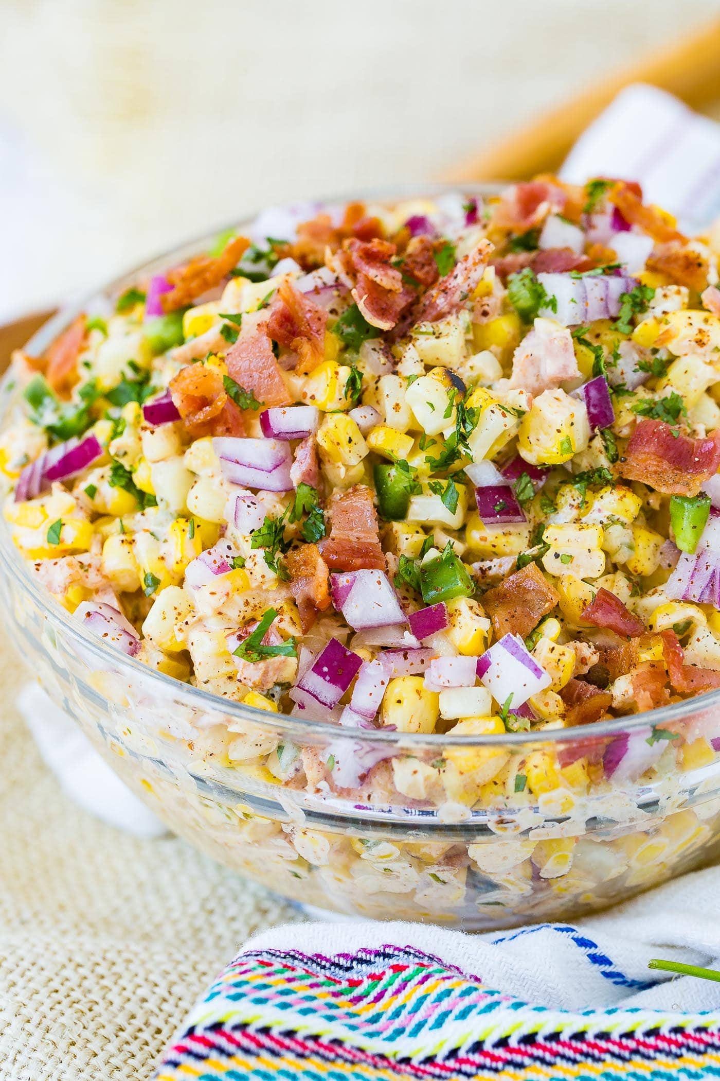 A bowl of Mexican corn salad topped with bacon and jalapeno.