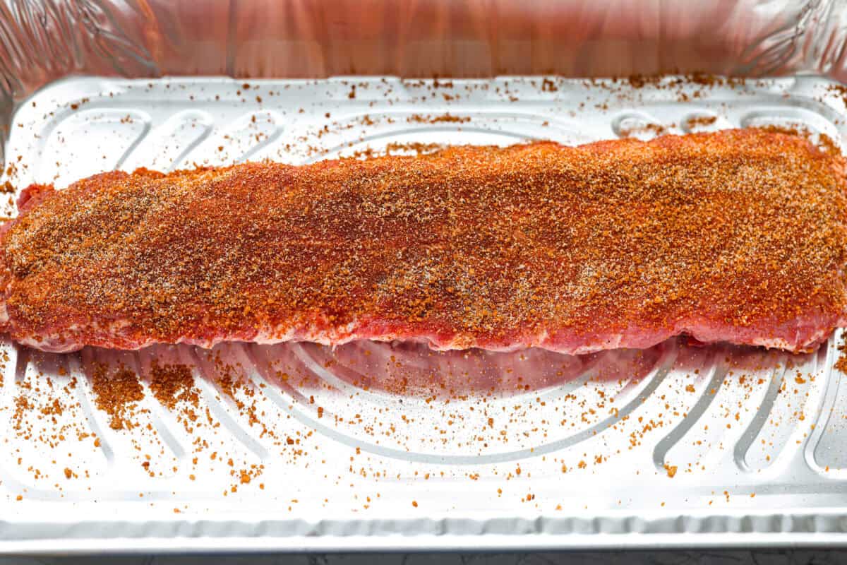 Rack of ribs with seasoning rubbed all over it. 