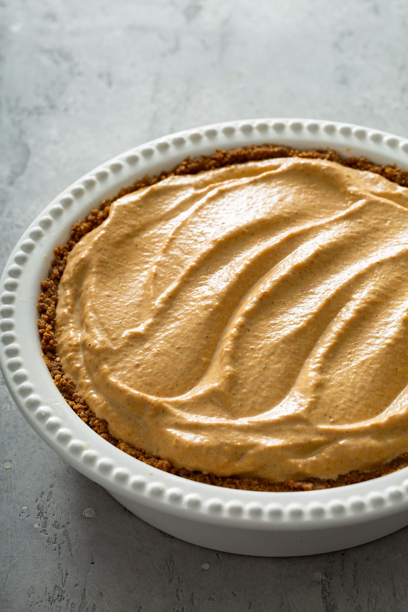 A whole pumpkin ice cream pie in a white pie dish.
