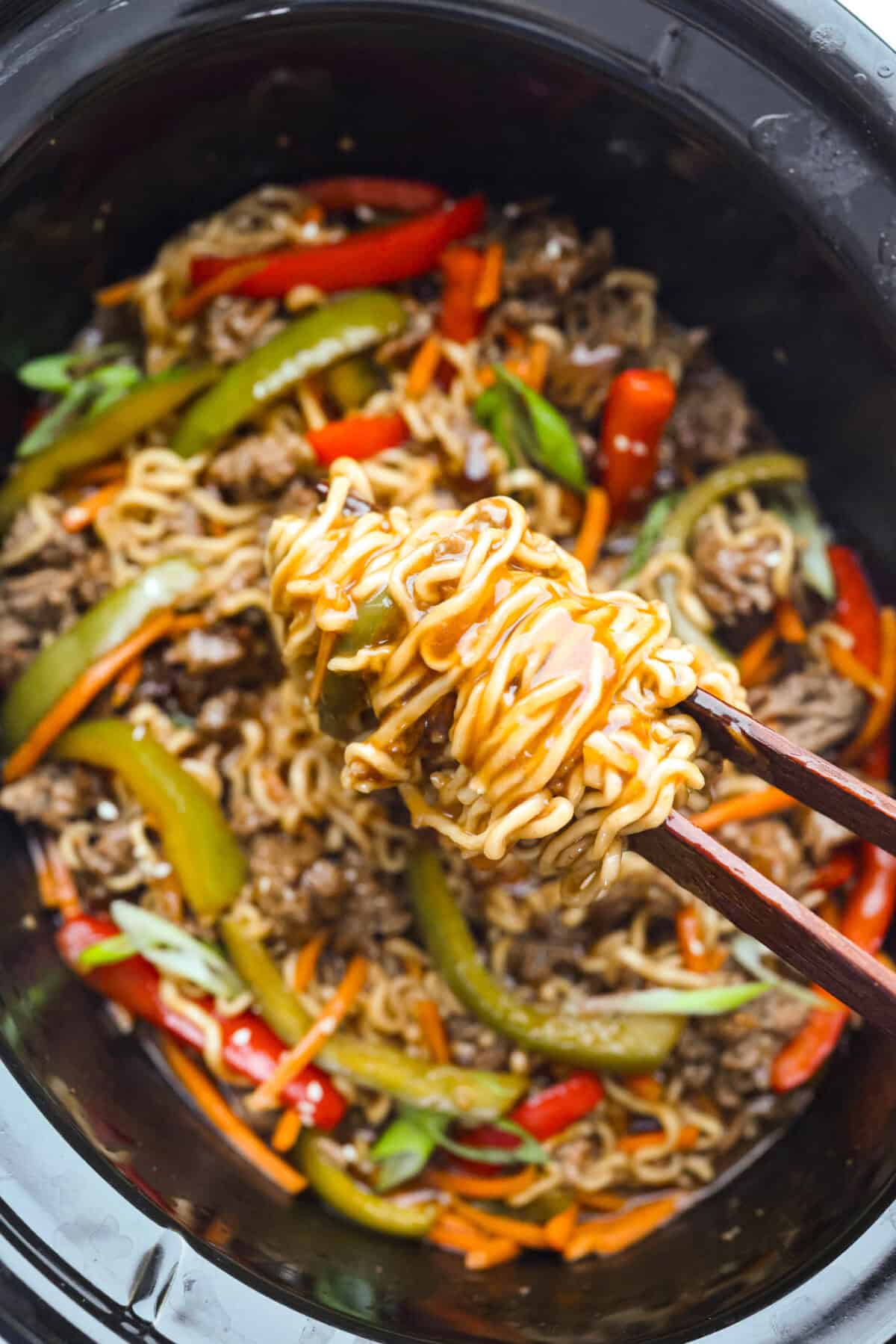 Close up shot of the slow cooker ramen noodles being lifted up by chopsticks. 