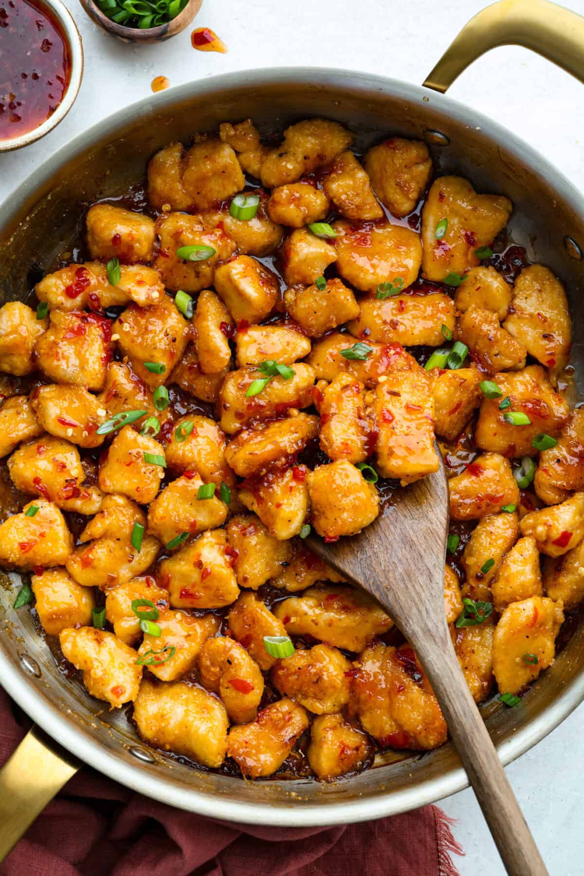 Pan of sweet chili chicken garnished with green onions. 