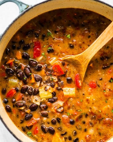 A pot of black bean soup with a wooden spoon.