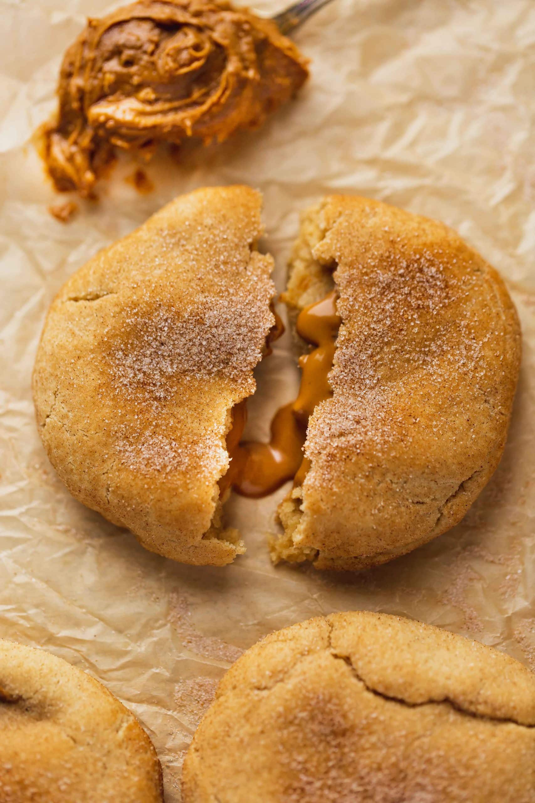 A biscoff stuffed snickerdoodle that is broken in half showing the biscoff oozing our from inside.