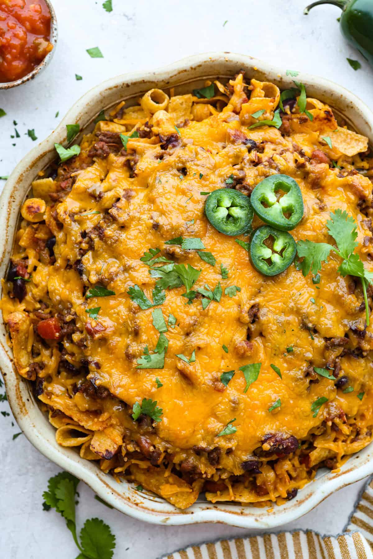Overhead shot of Frito chili pie garnished with cilantro and jalapeños. 