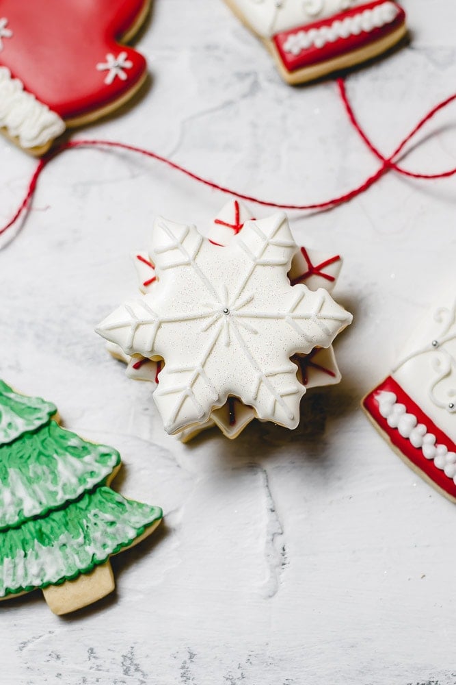 Christmas sugar cookies. White snowflake with white accents, and a green tree with white snow.