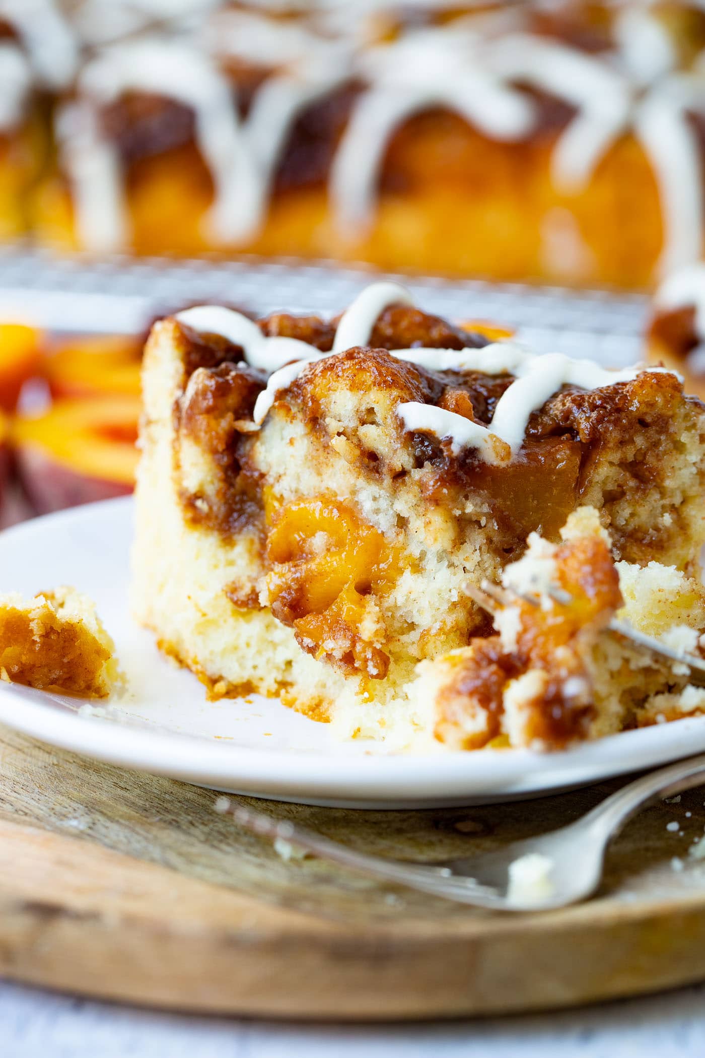 a photo of a single piece of peach coffee cake that has been cut into by a fork