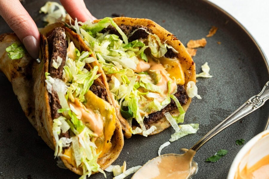 a hand picking up a smash burger taco a hand picking up a smash burger taco
