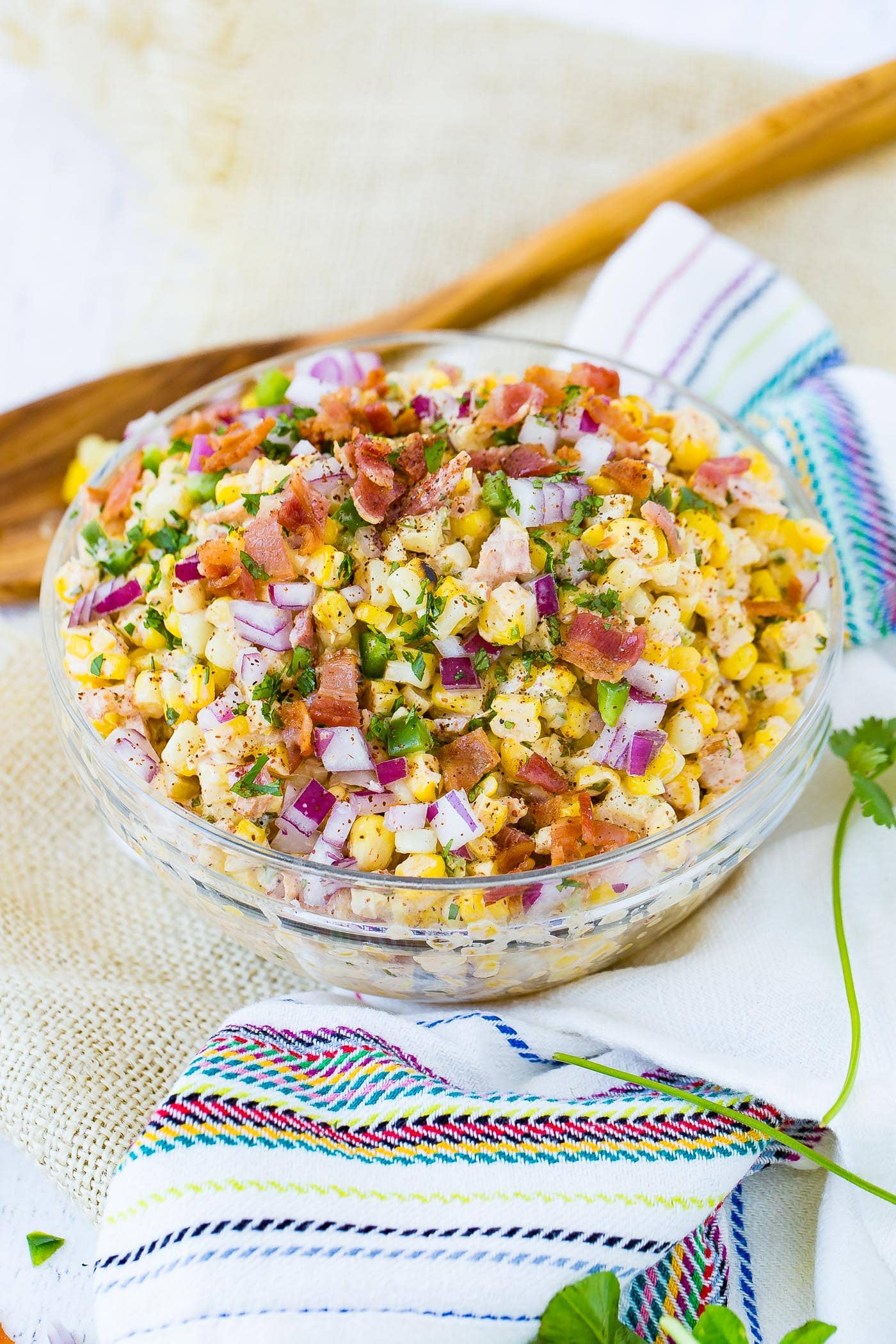 A bowl of Mexican corn salad topped with bacon and jalapeno.