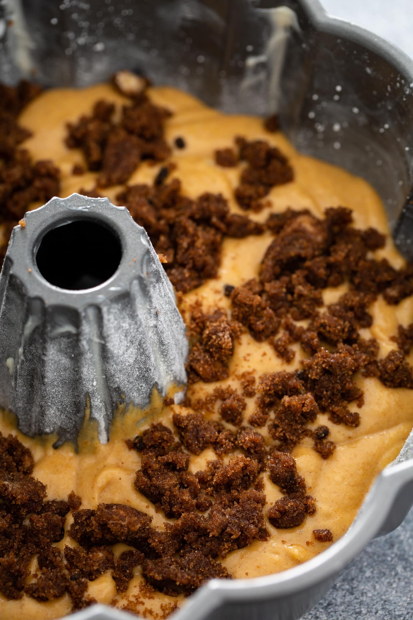 An unbaked pumpkin bundt cake in a bundt pan with cinnamon filling on top.