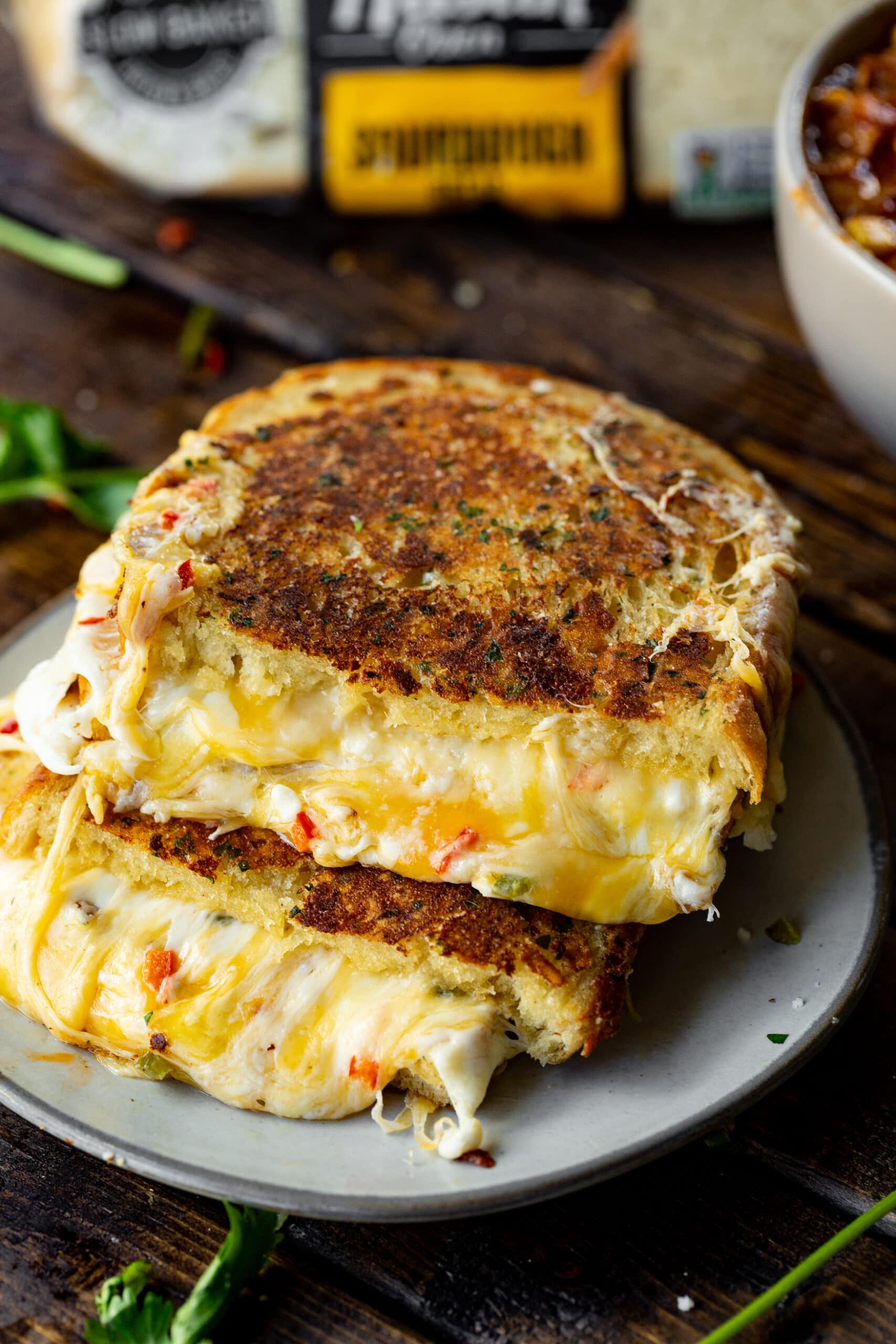 a photo of a grilled cheese sandwich that is golden on the outside and gooey with melted cheese in the middle. It has been cut in half and then stacked on top of each other so you can see the inside of the sandwiches.