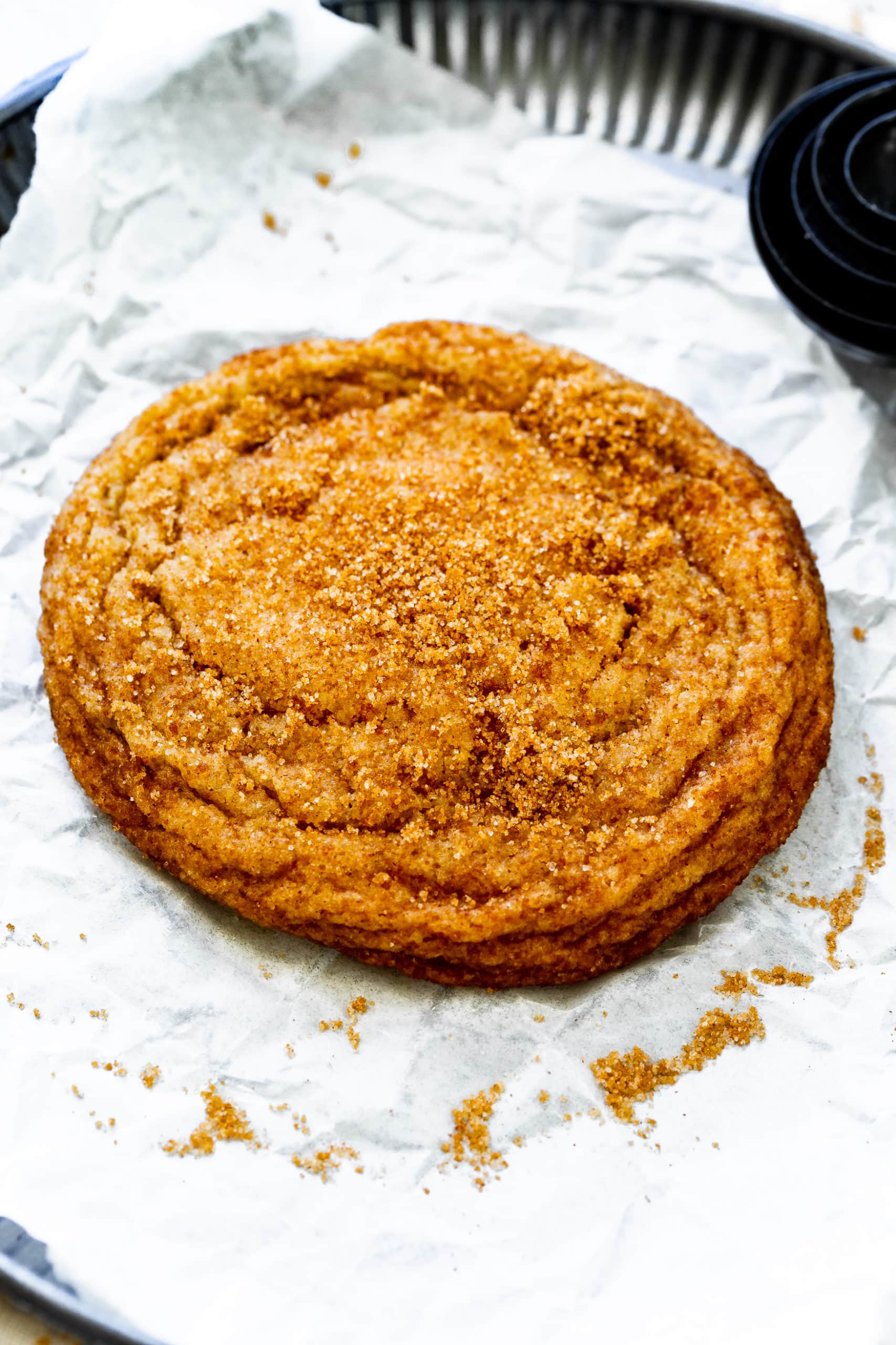 a photo of a single golden baked banana cookie covered in cinnamon sugar.