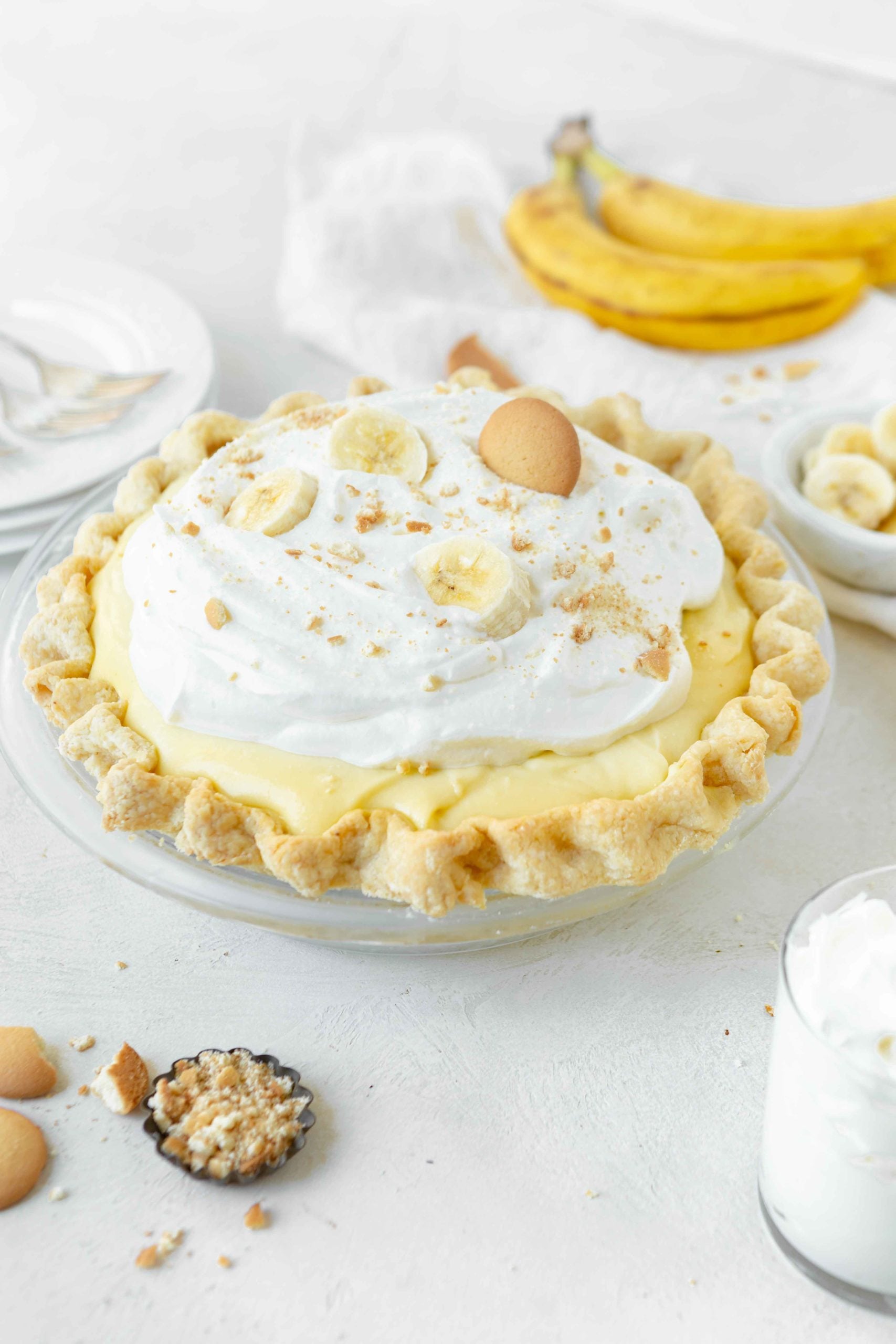 a photo of a whole banana cream pie topped with whipped cream, slices of banana, and a Nilla Wafer and Nilla Wafer crumbles.