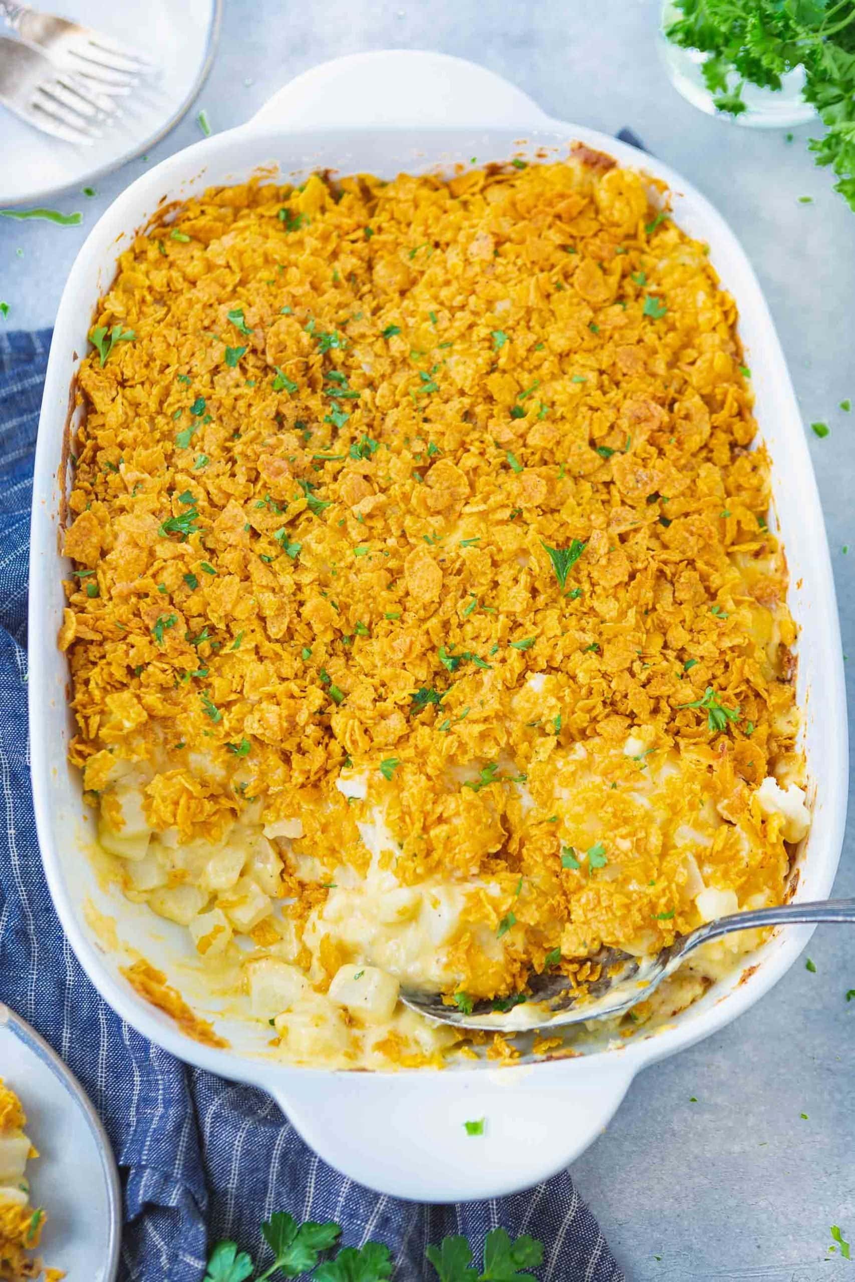 a photo of a casserole dish full of cheesy potato casserole with a few serving removed.