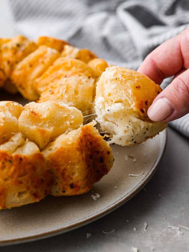 A piece of garlic pull-apart bread being picked up.