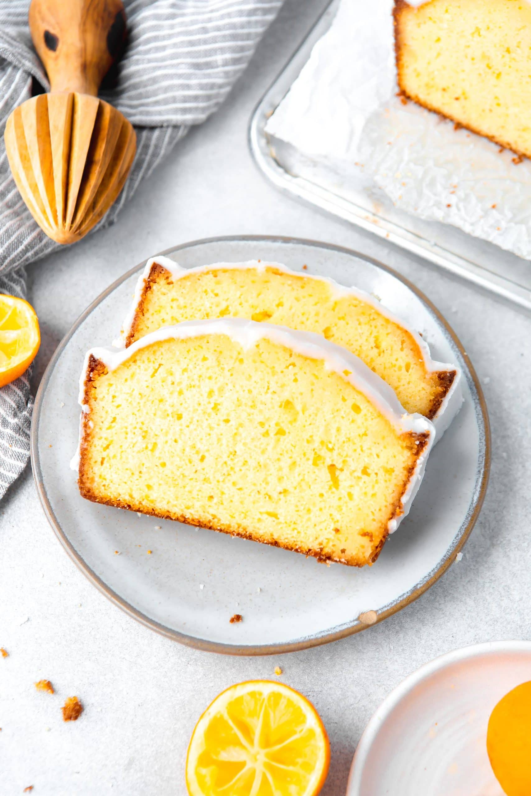 a photo of two slices of lemon loaf cake laying on a white plate.