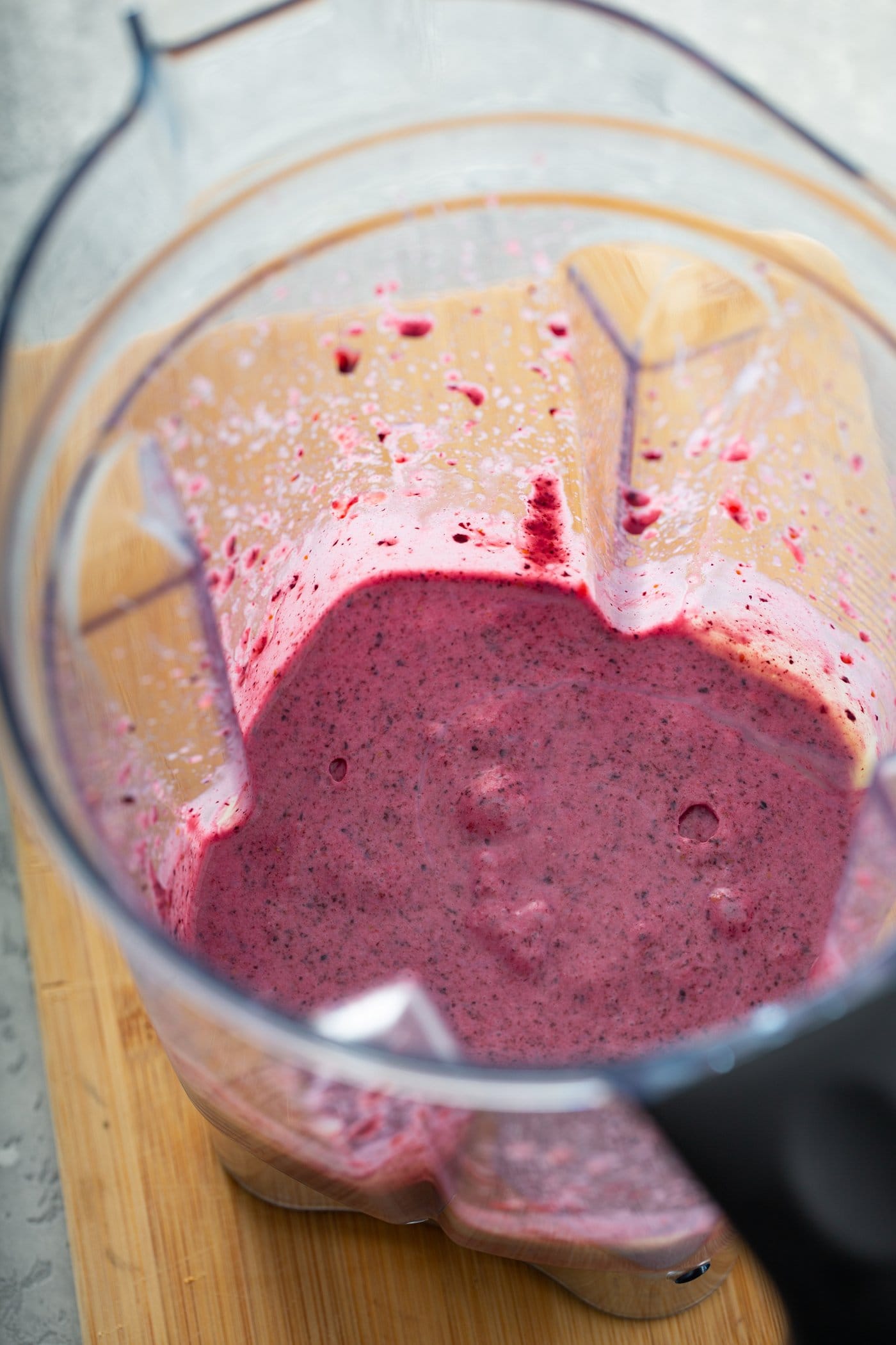 A blender container with pureed filling for the pie. It is smooth, pink, and has bits of pureed berries in it.