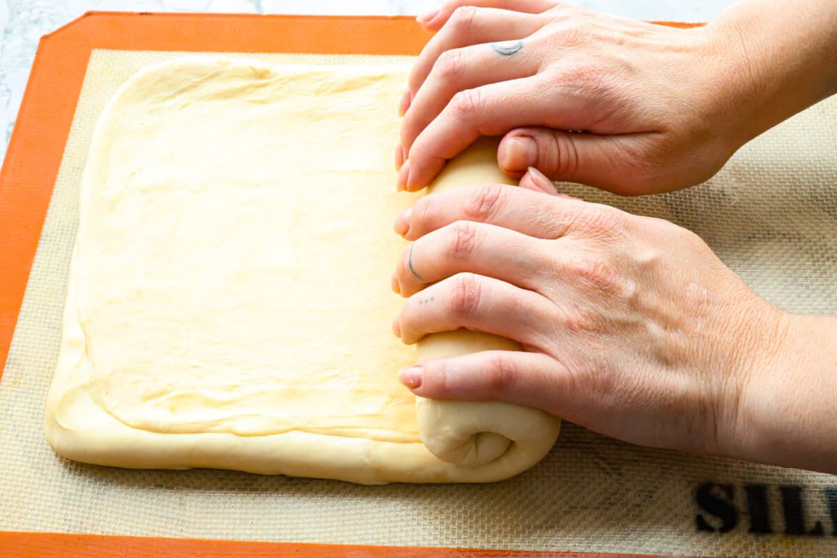 Overhead shot of someone rolling up dough. 