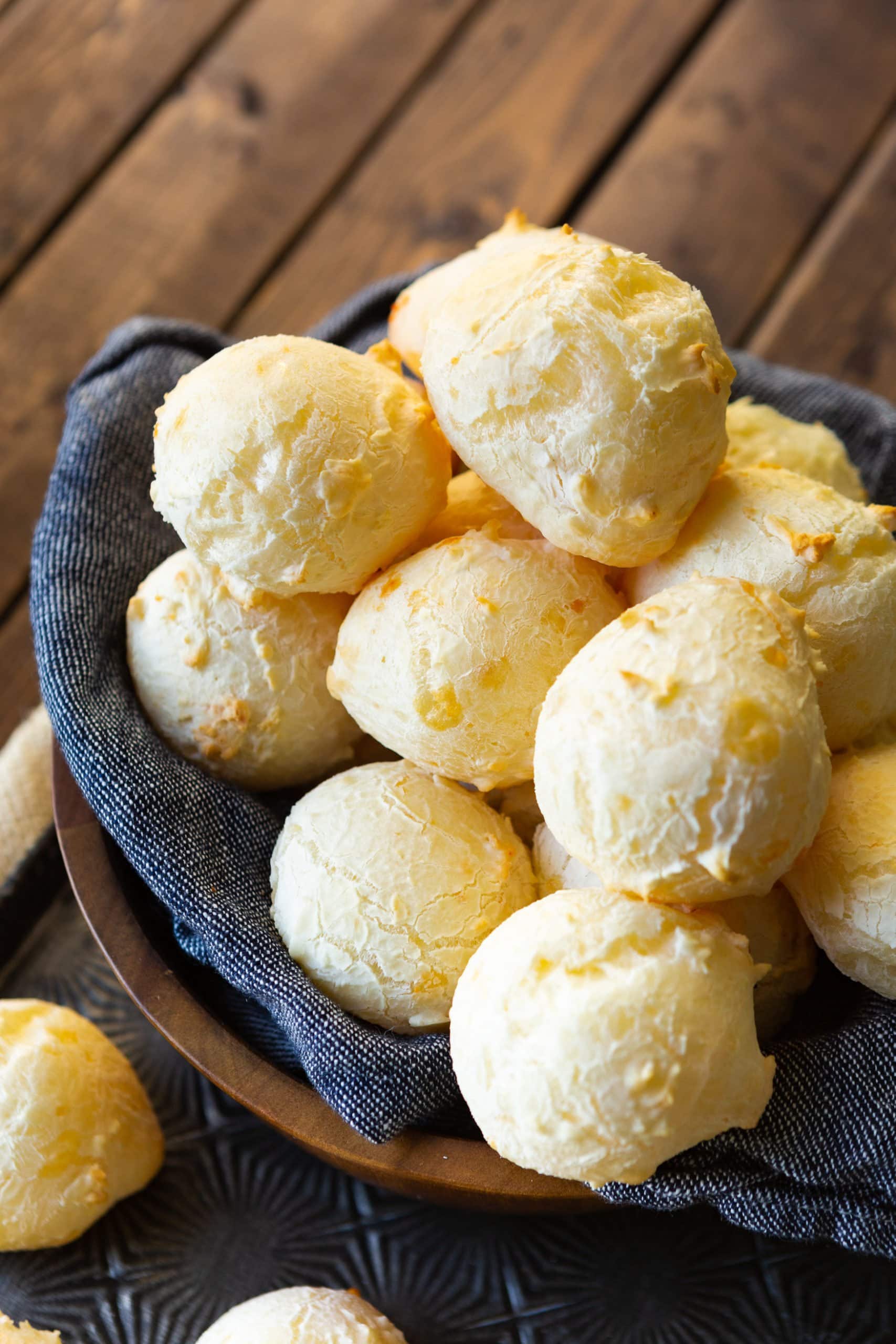 a photo of several small round cheese breads sitting on a dark wooden table.