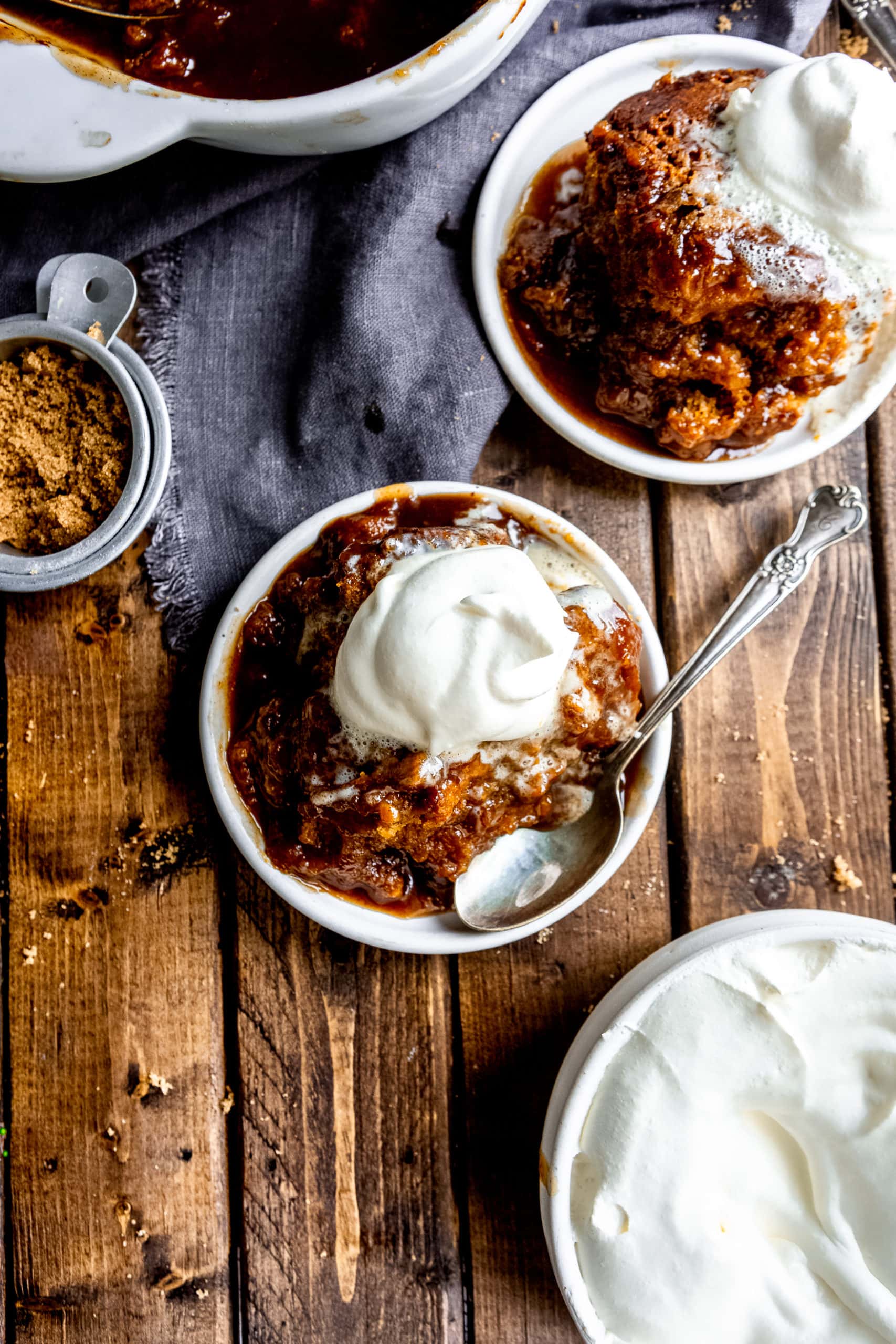 a photo of a single serving of pumpkin lava cake on a small white saucer with a silver spoon sitting next to it and topped with a dollop of whipped cream.
