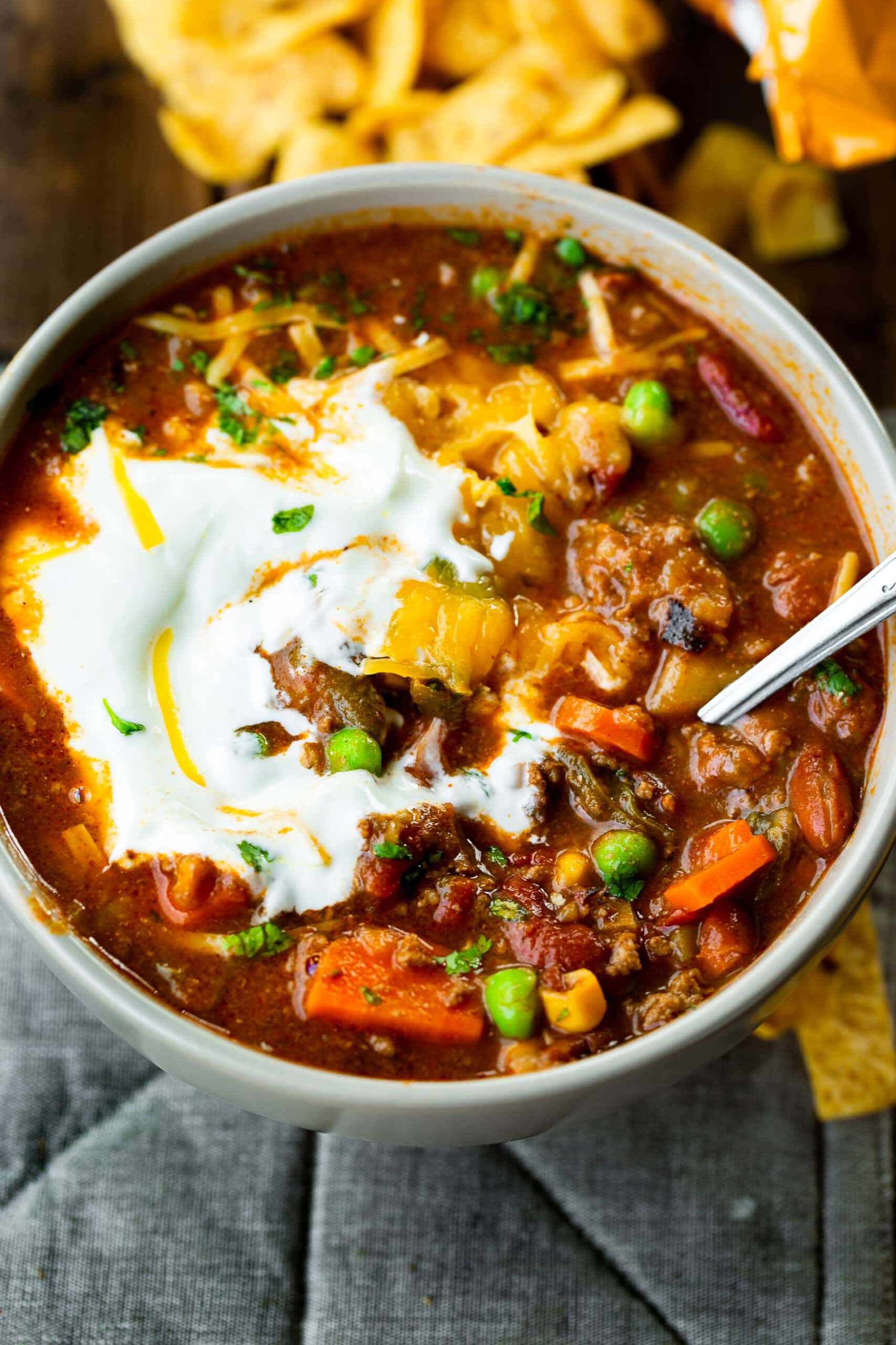 a photo of a bowl full of taco stew topped with some melty sour cream and shredded cheddar cheese. a photo of a bowl full of taco stew topped with some melty sour cream and shredded cheddar cheese.